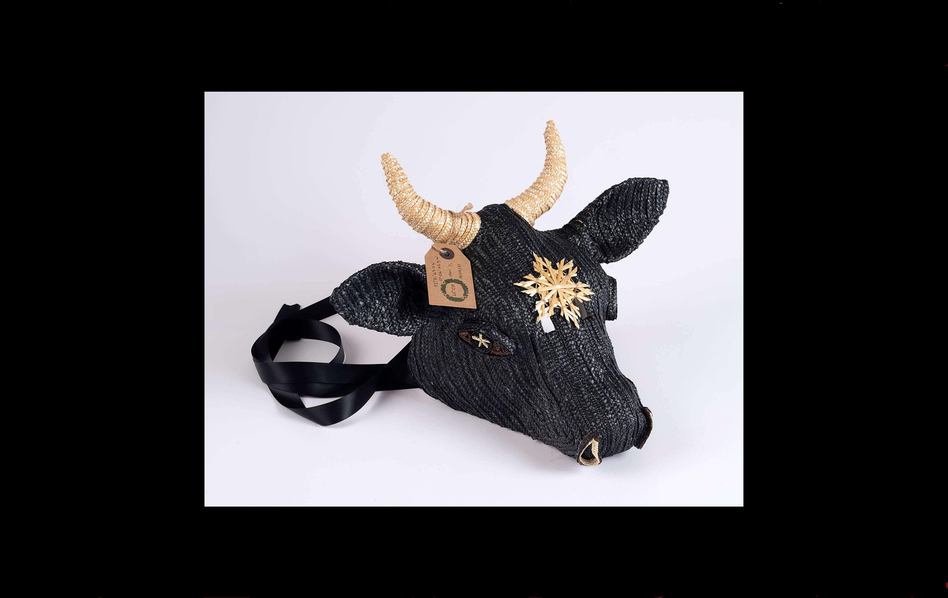 Photograph of a cow's head made with black straw and with a yellow straw woven star on its forehead