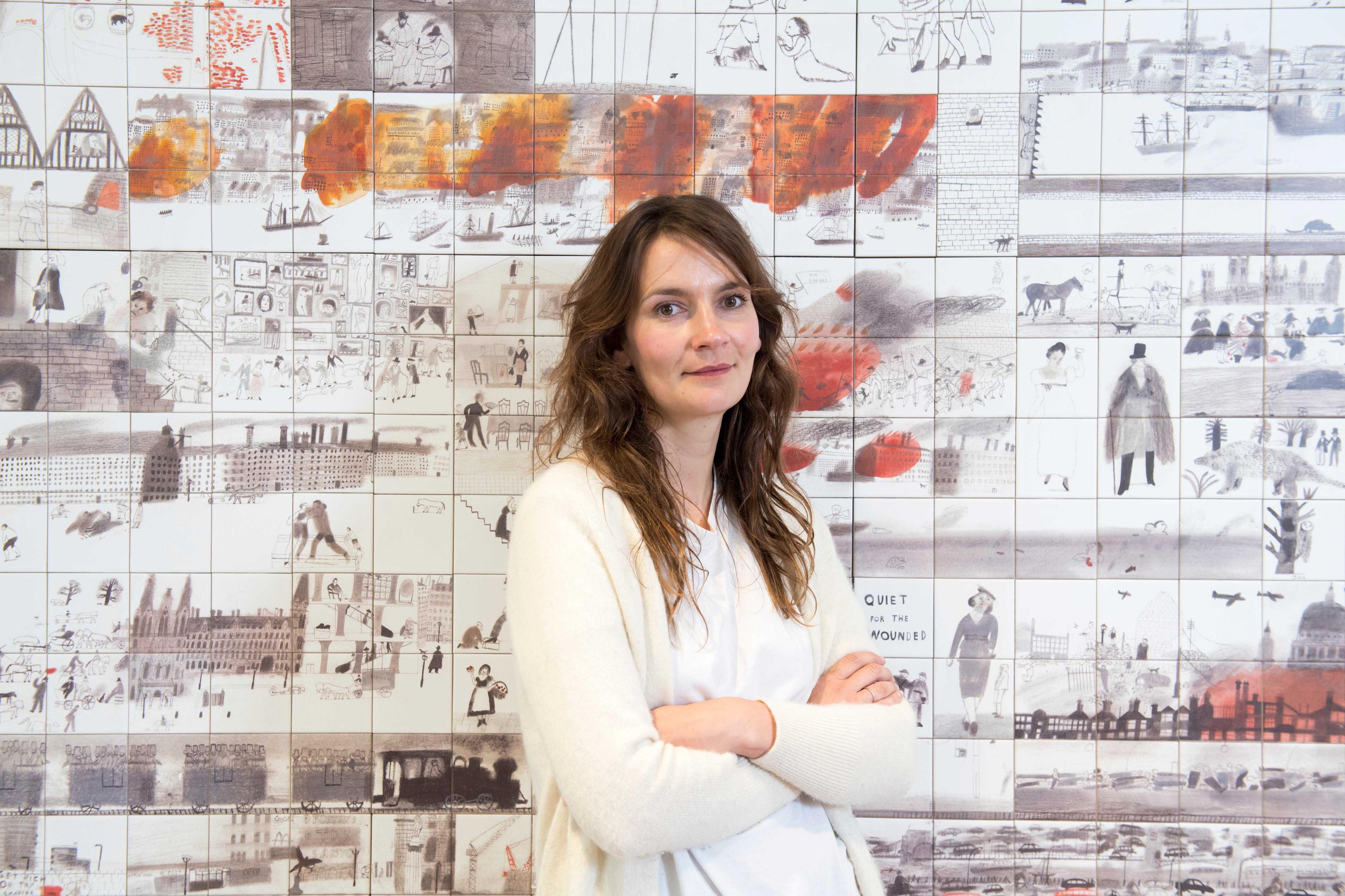 A person standing in front of a large tiled mural.