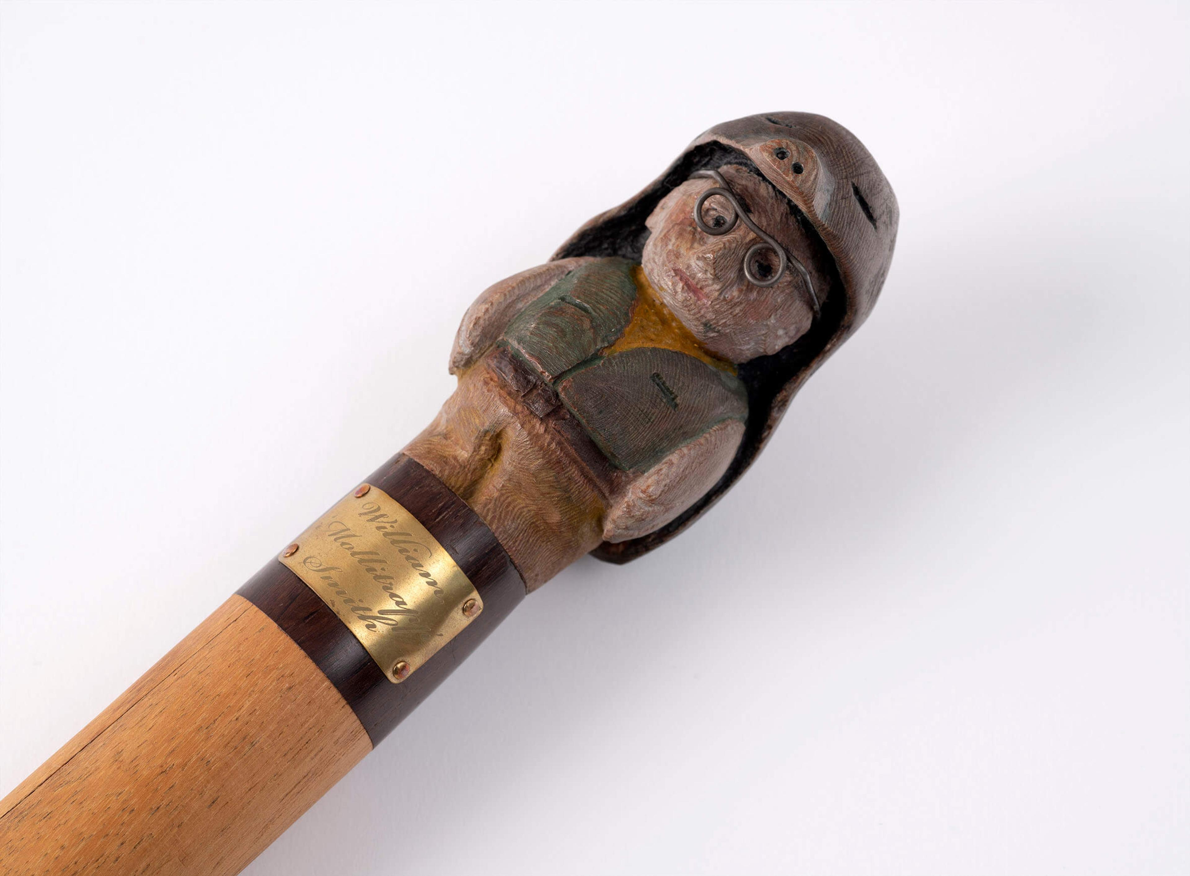 Photograph of a pole topped by a brass plaque and a wooden carving of a man wearing a mole costume