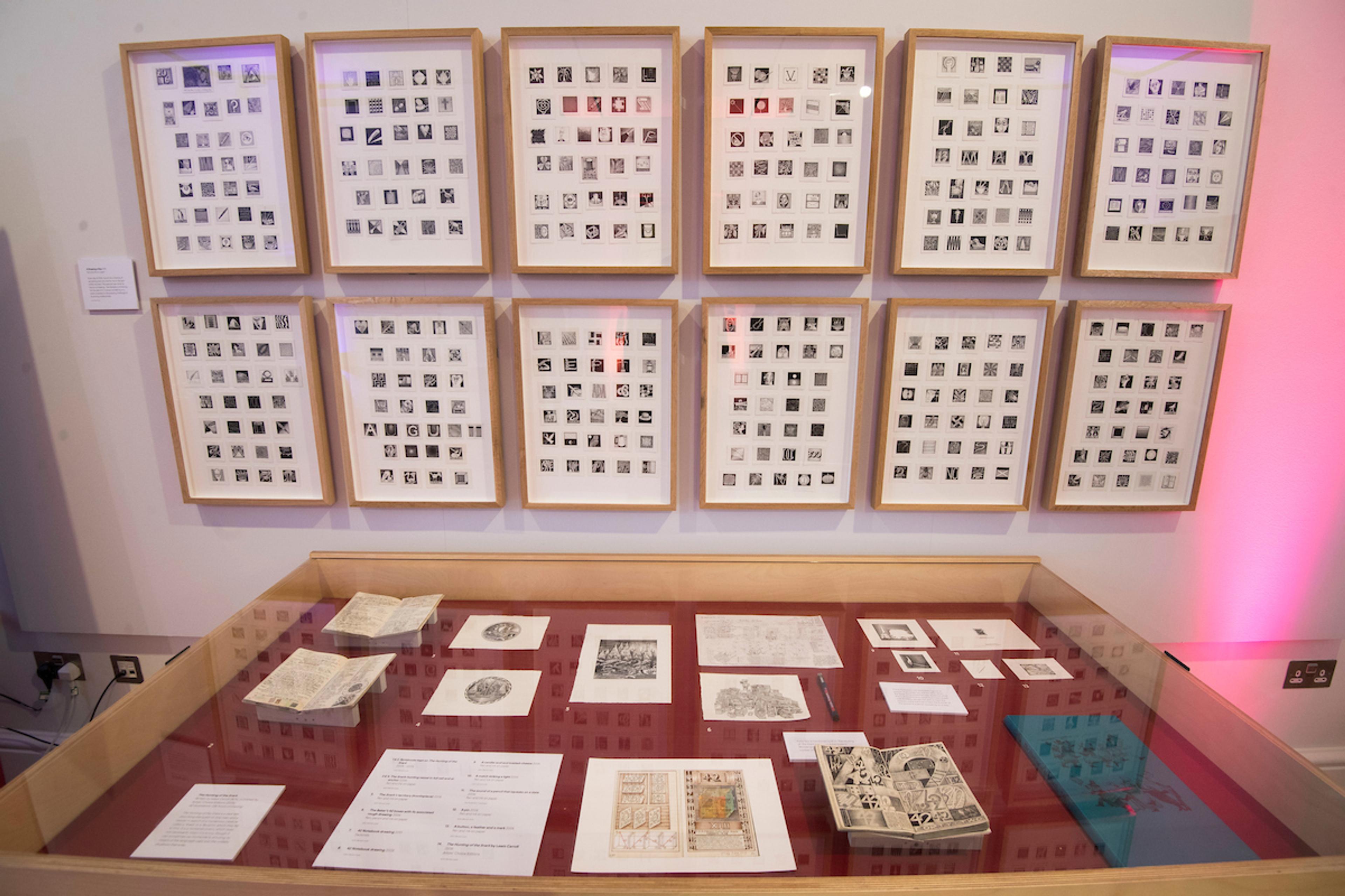 Photograph of framed artwork and a display case at the exhibition