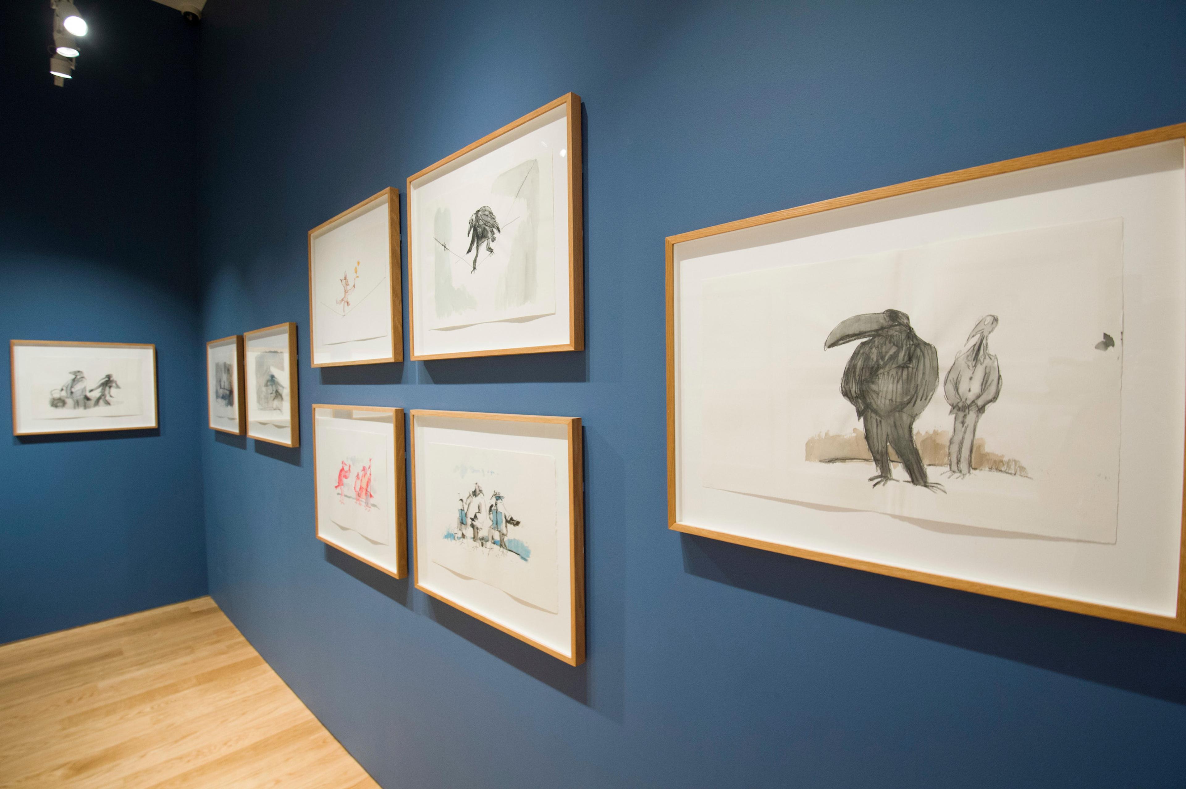 Framed illustrations displayed on a gallery wall.