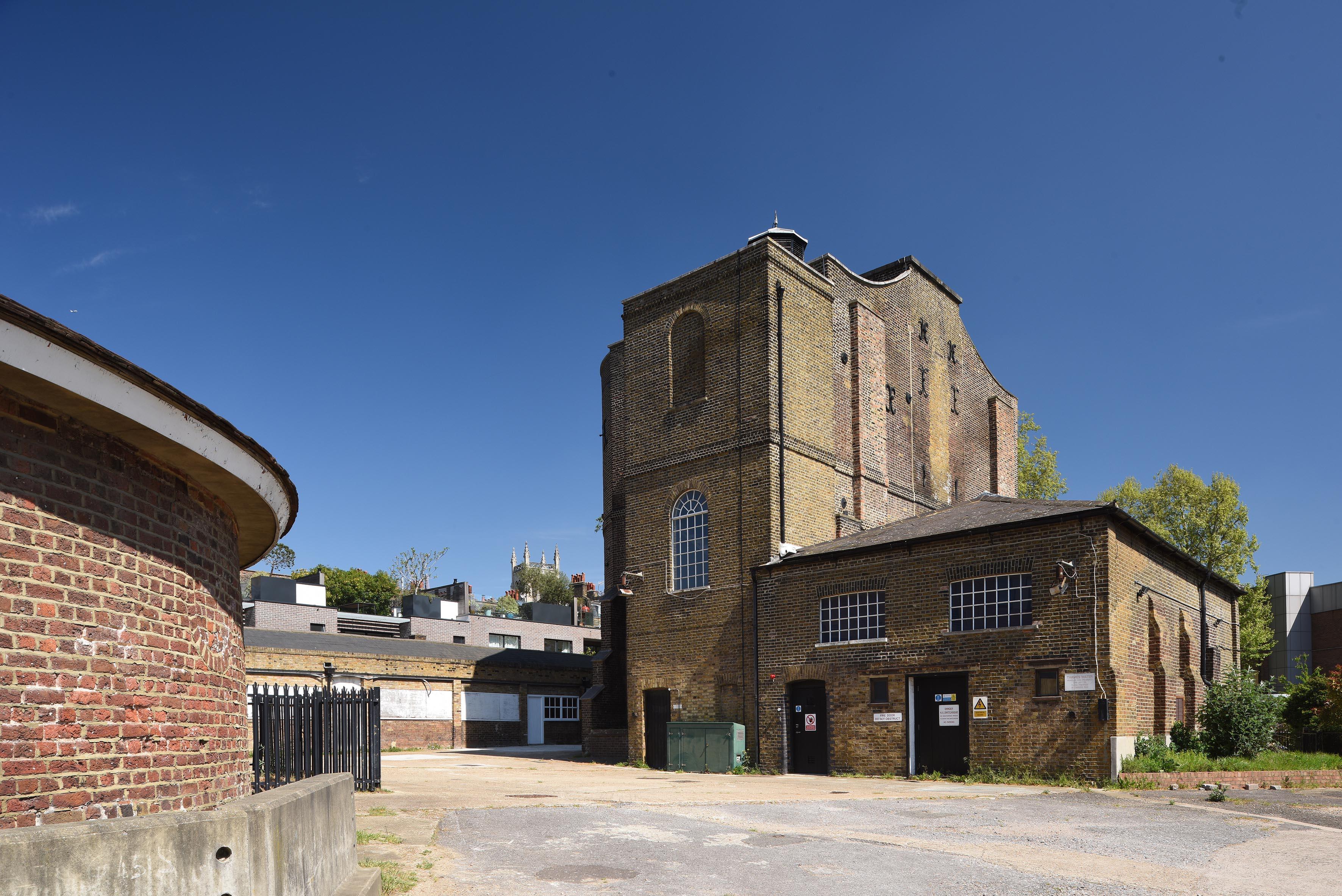 Photograph of a derelict heritage site with brick buildings and a cobbled path.