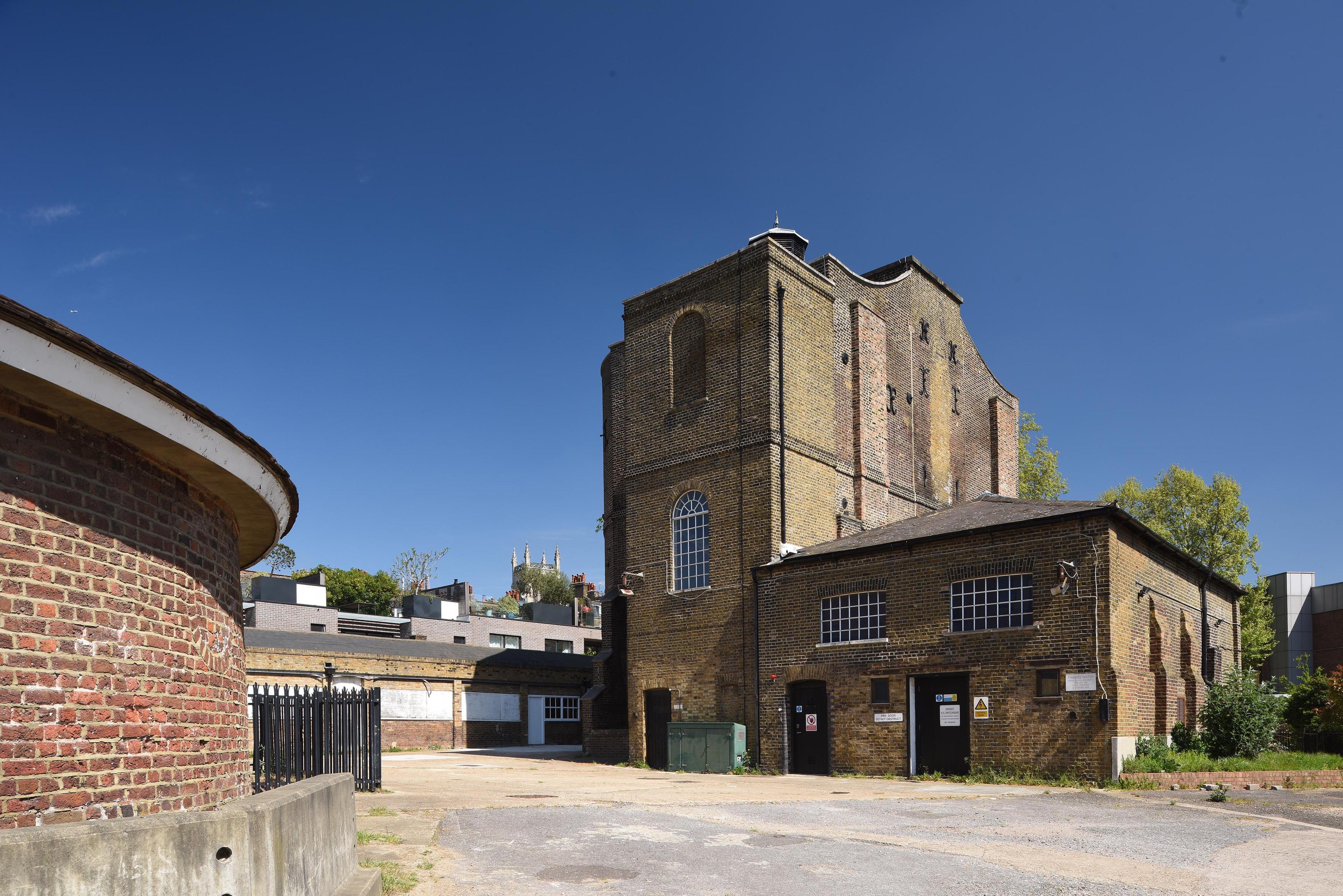 Photograph of a derelict heritage site with brick buildings and a cobbled path.