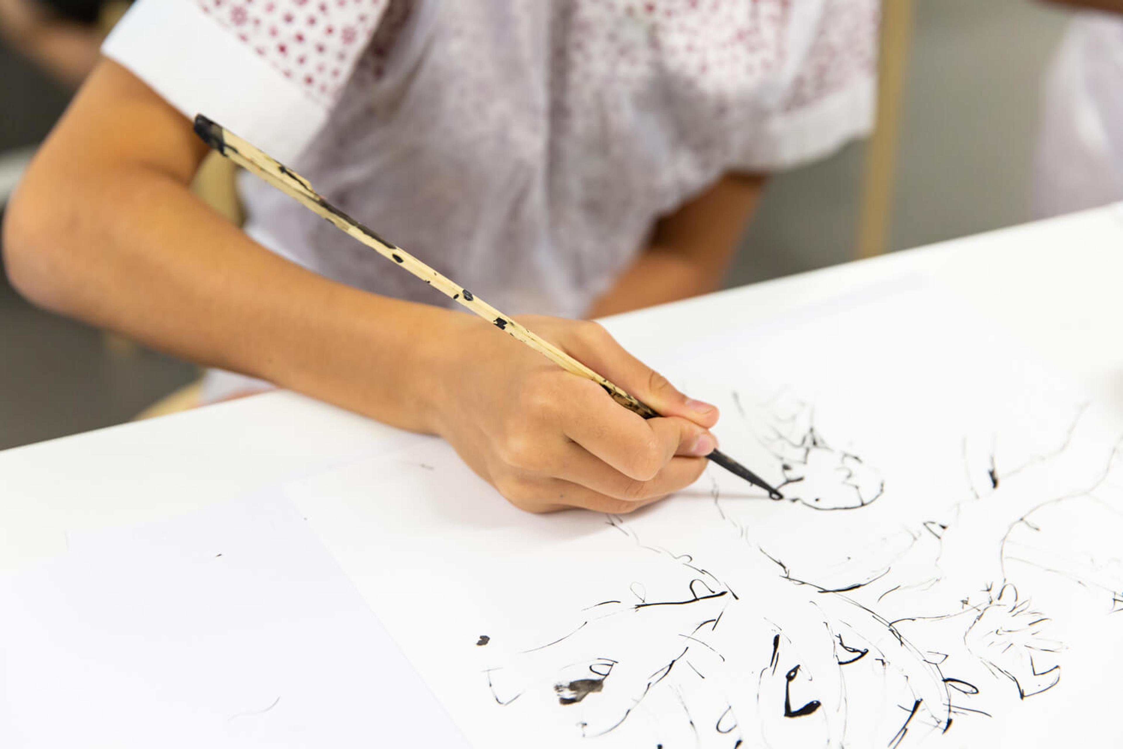 Photograph of a child painting with a long paint brush.