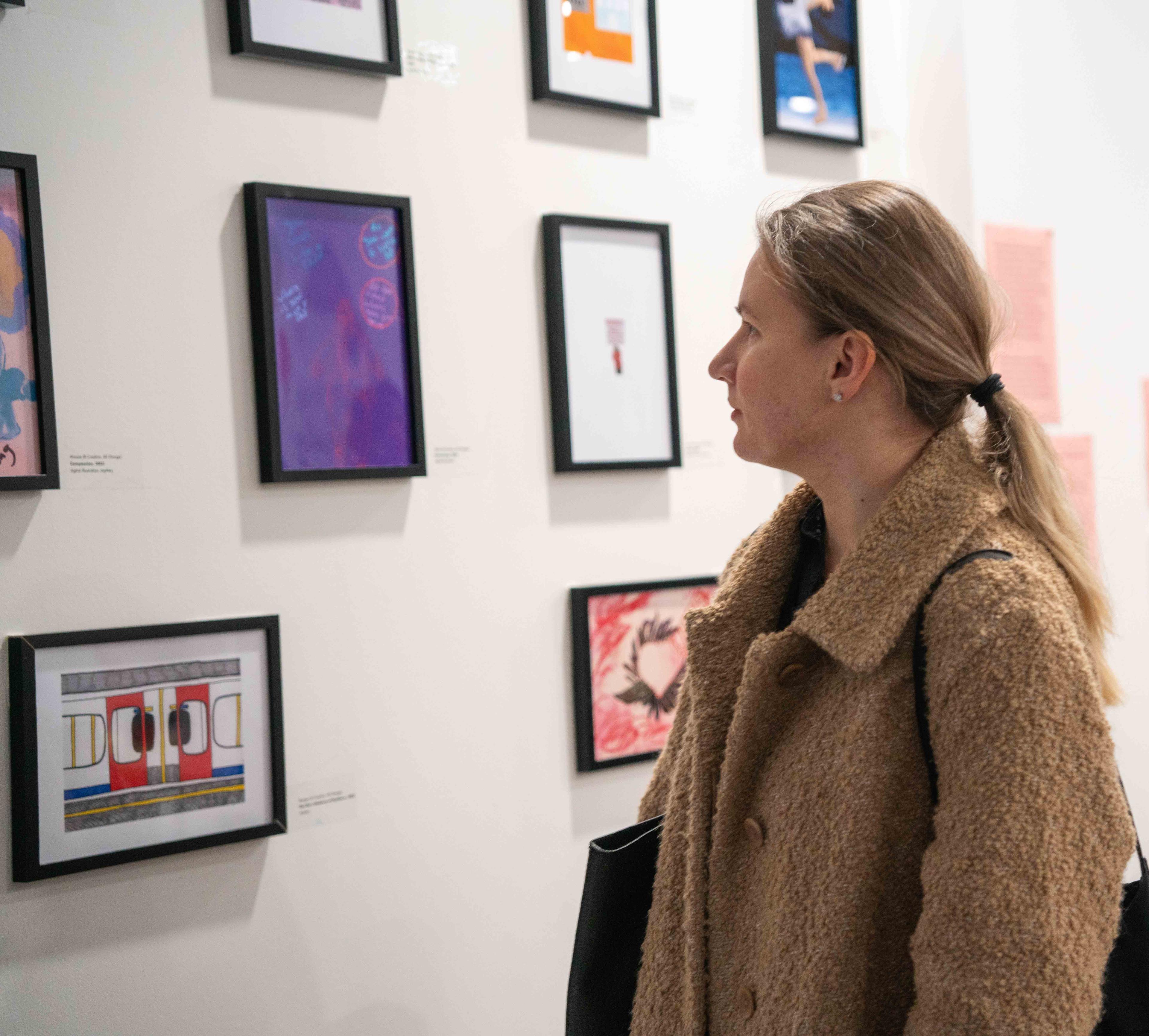 Person looking at framed illustrations on a wall.