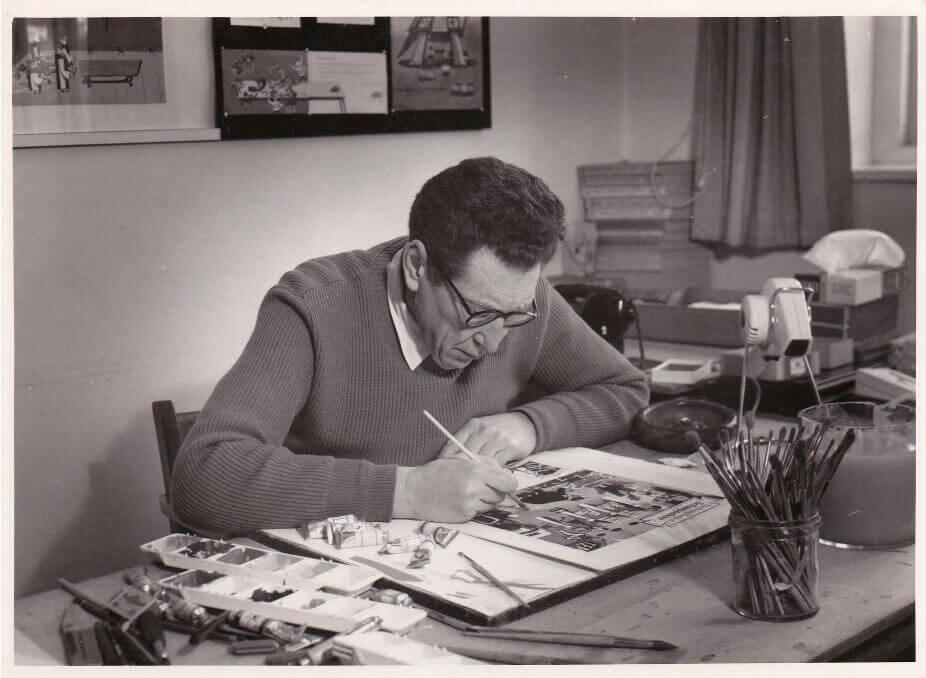 Black and white photograph of George Him drawing at his desk