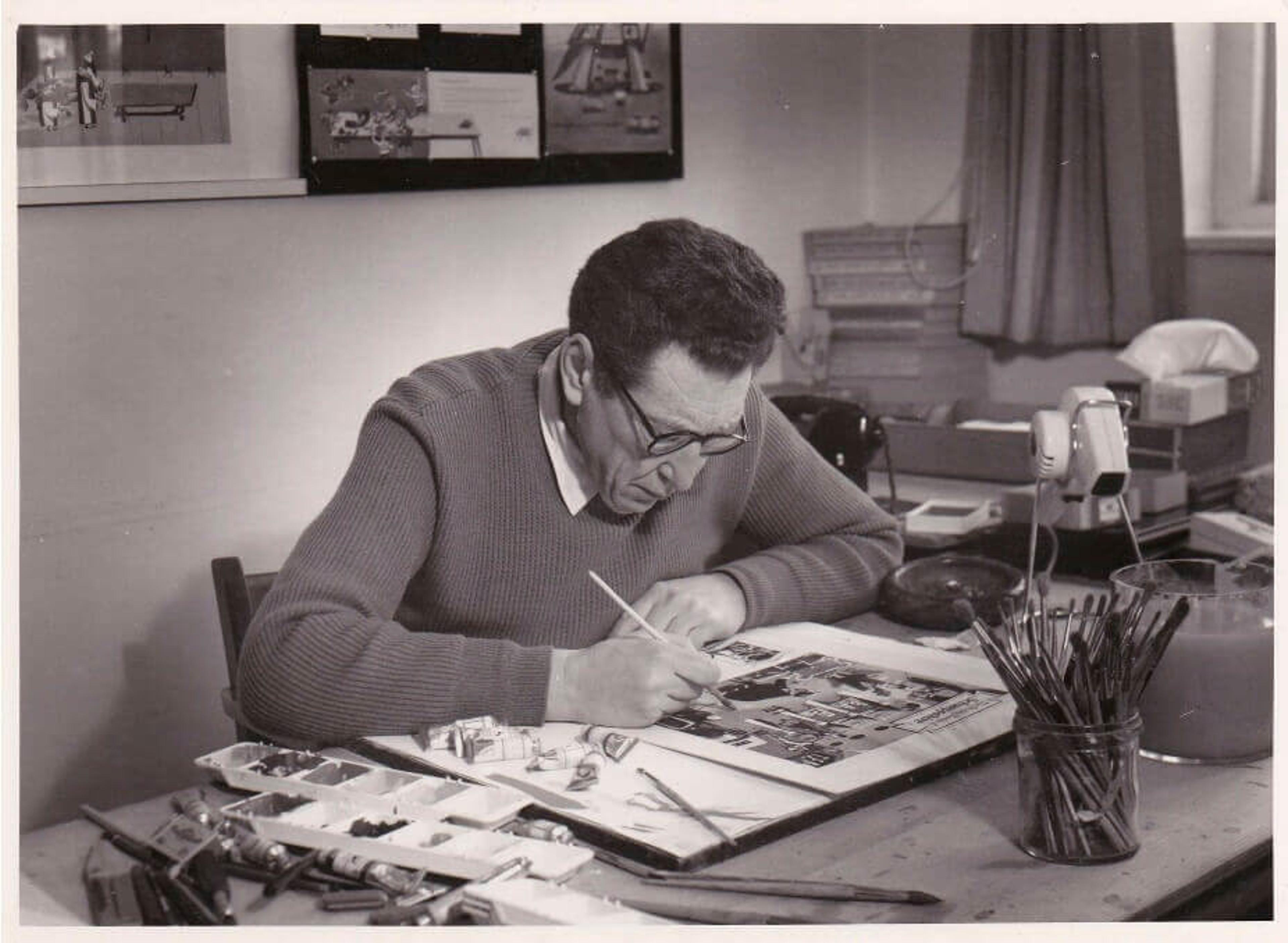 Black and white photograph of George Him drawing at his desk