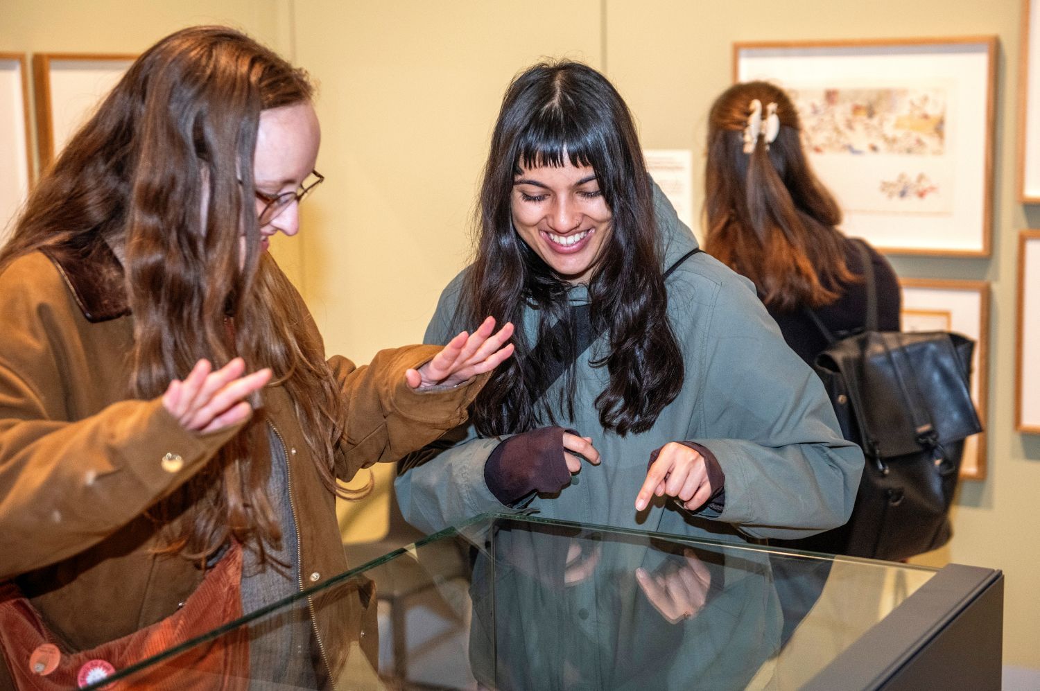 Two women pointing into a glass case and smiling.