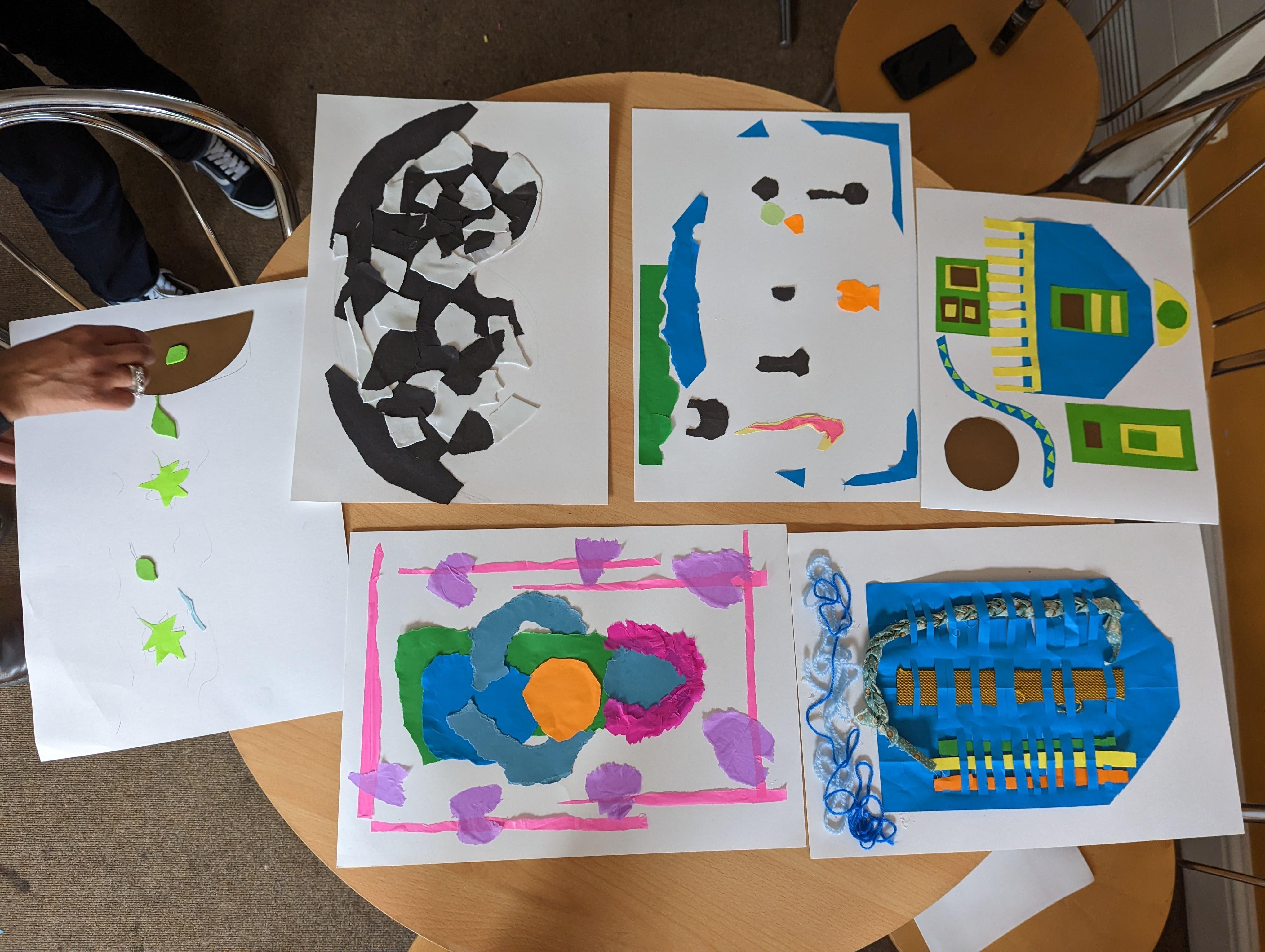A collection of colourful collages laid out on a round table.
