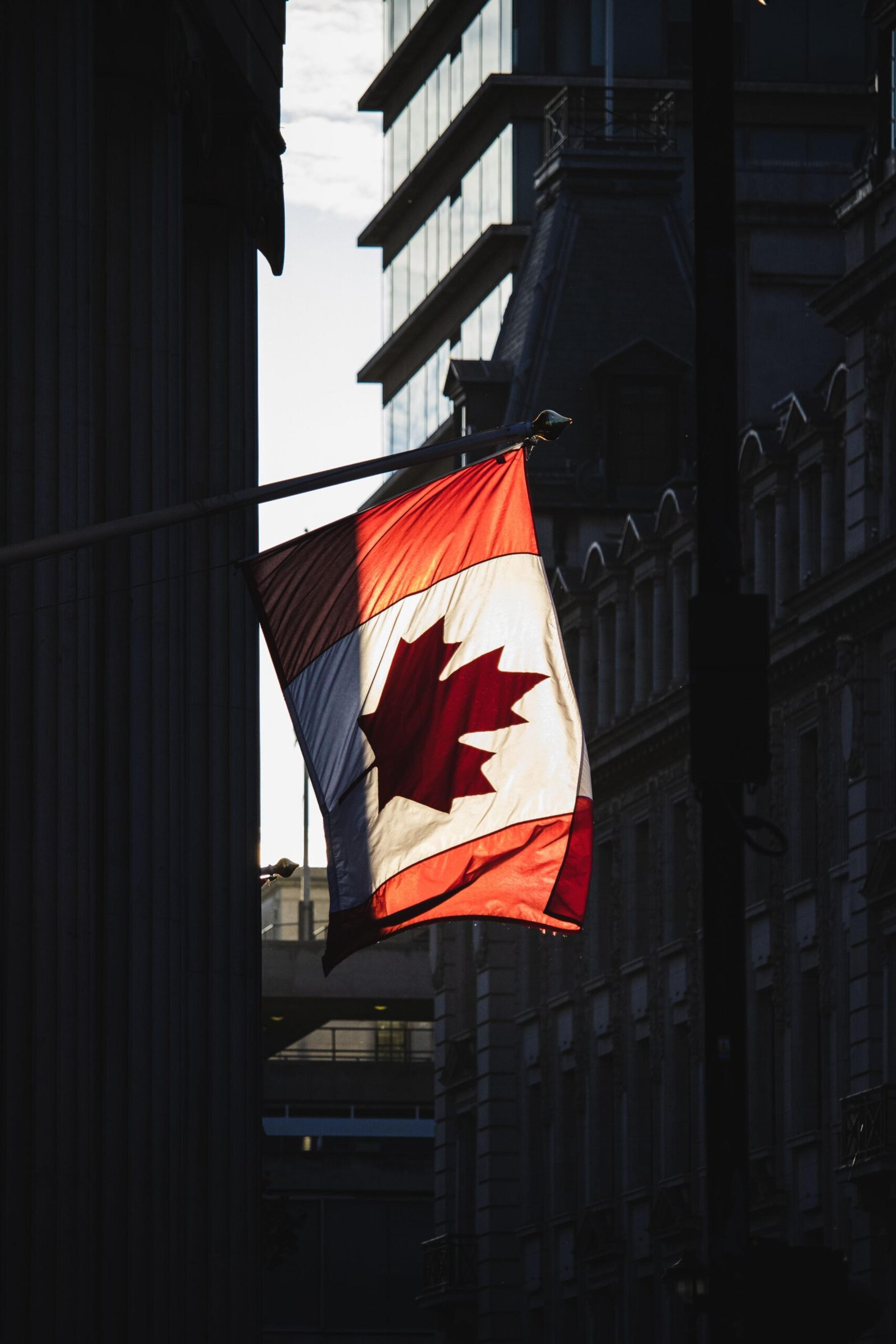 A Canadian flag waving prominently in a sunlit street in London, showcasing cultural diversity.