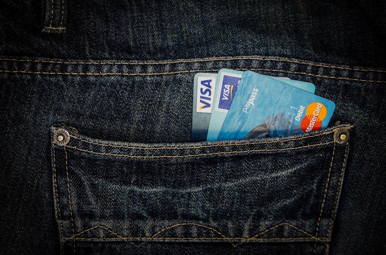 Payment cards and cash in a jeans pocket, illustrating the fees a visa agency in Kochi charges upfront.