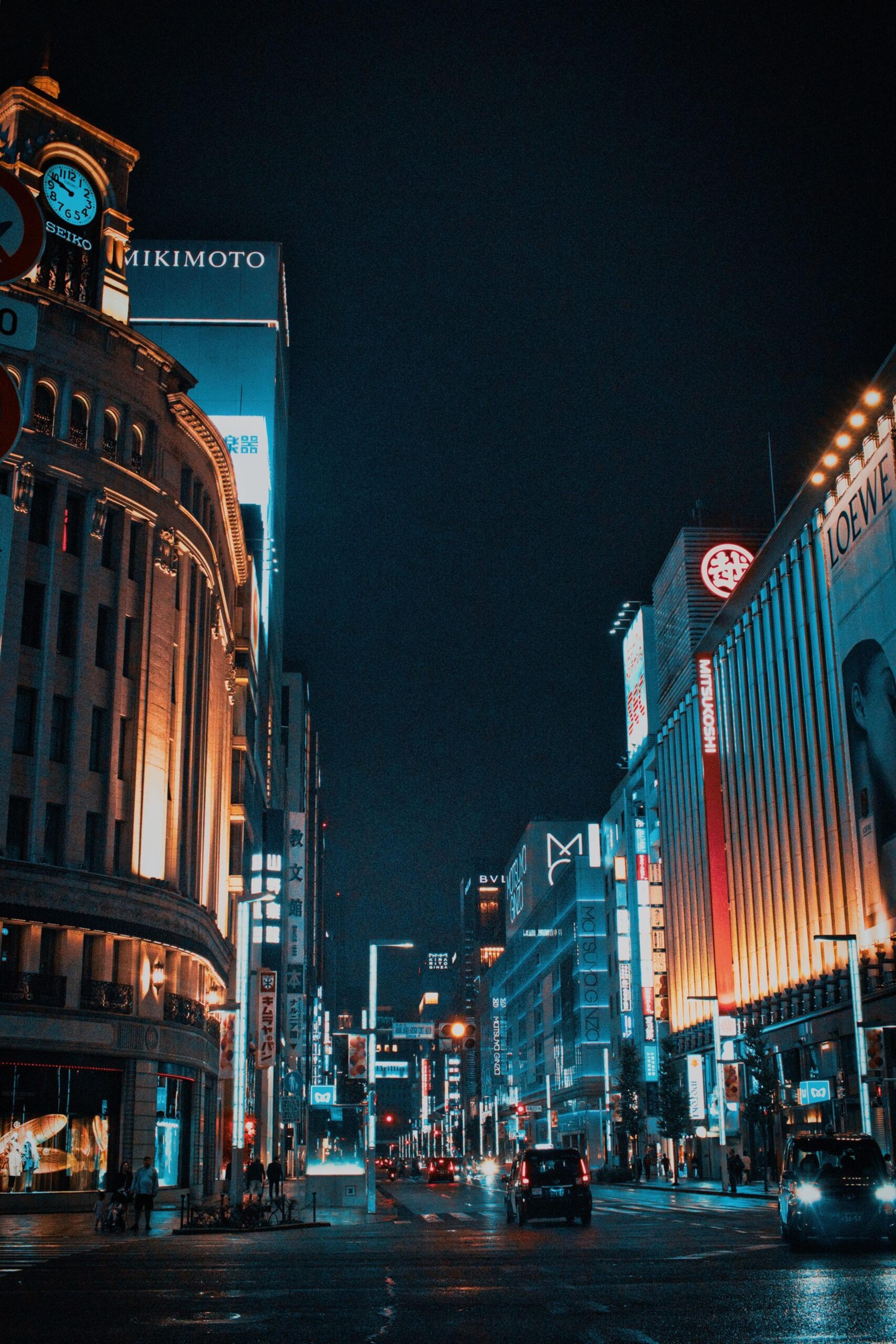 Experience the vibrant nightlife of Ginza, Tokyo, in this stunning street view illuminated by towering neon lights.