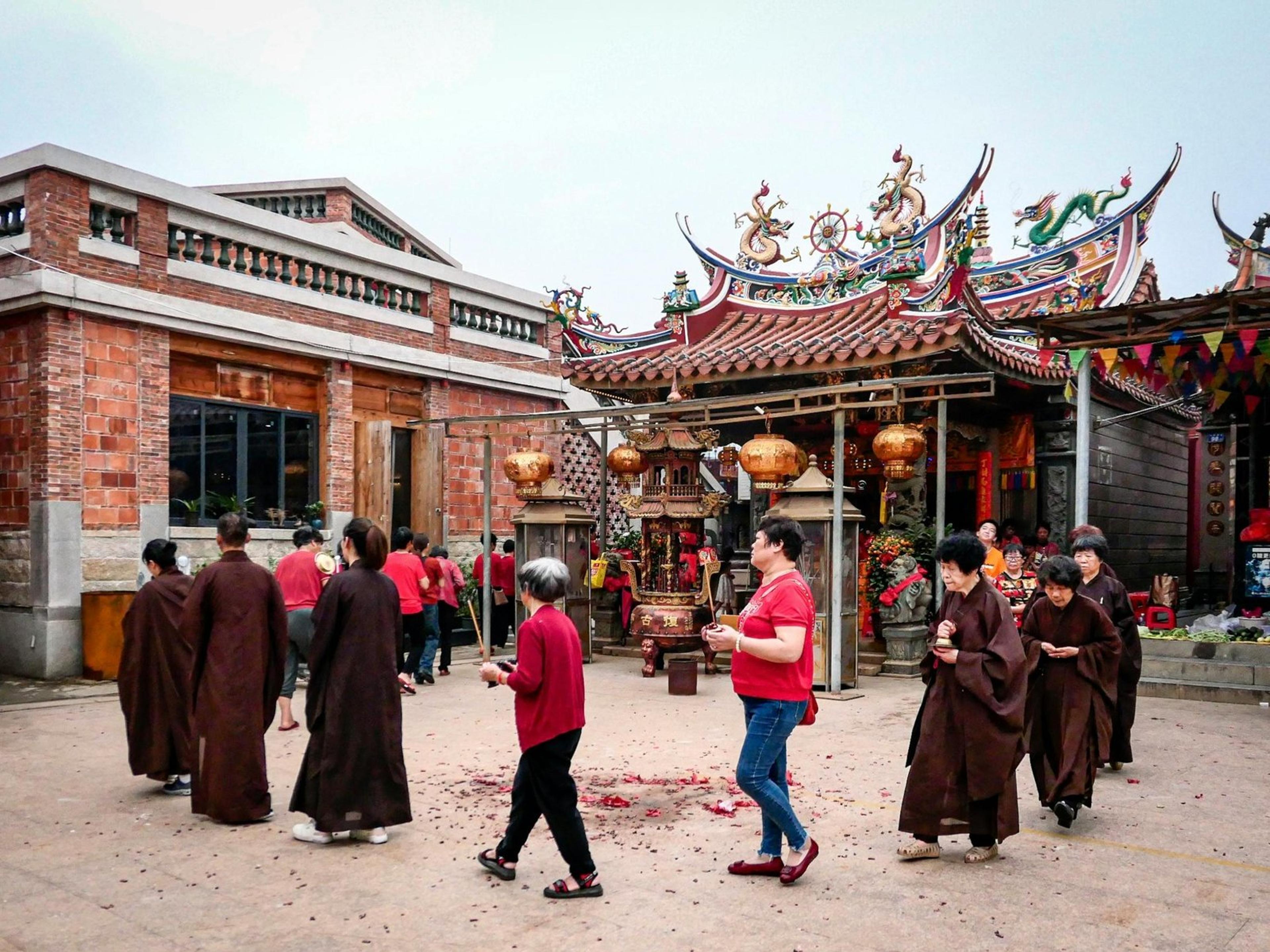 People participating in a spiritual ritual outside a traditional Asian temple.