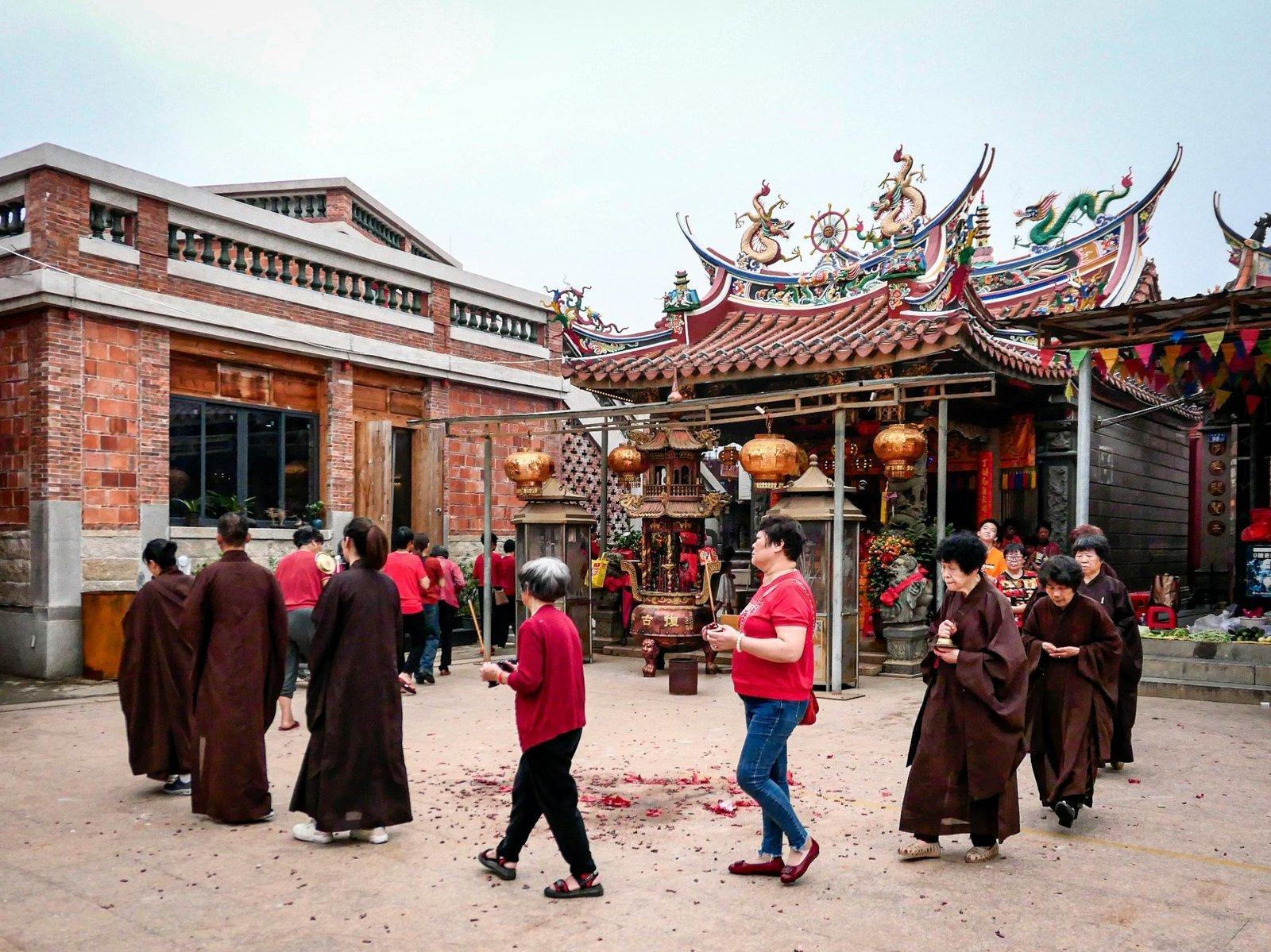 People participating in a spiritual ritual outside a traditional Asian temple.