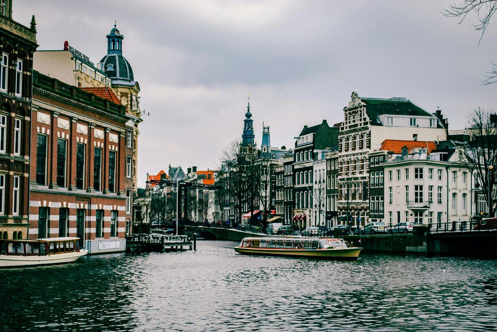 Charming canal scene in Amsterdam with historic architecture and a passing boat.