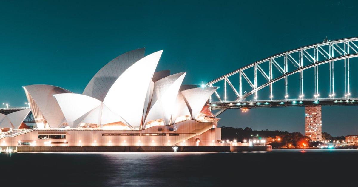 Stunning night view of Sydney Opera House and Harbour Bridge, beautifully illuminated against a clear sky.