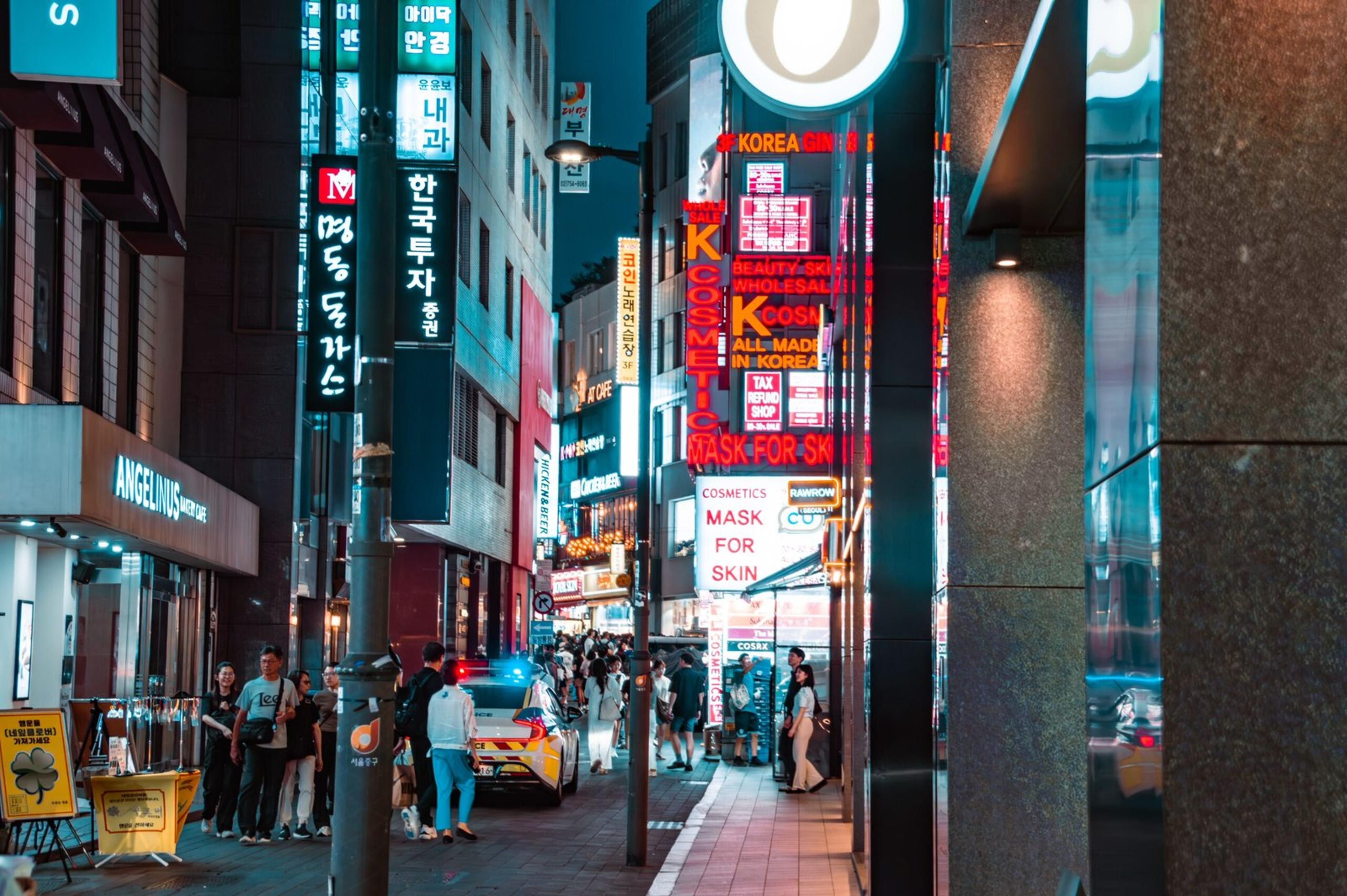 A bustling night scene in Myeongdong, Seoul, showcasing vibrant signs and street activity.