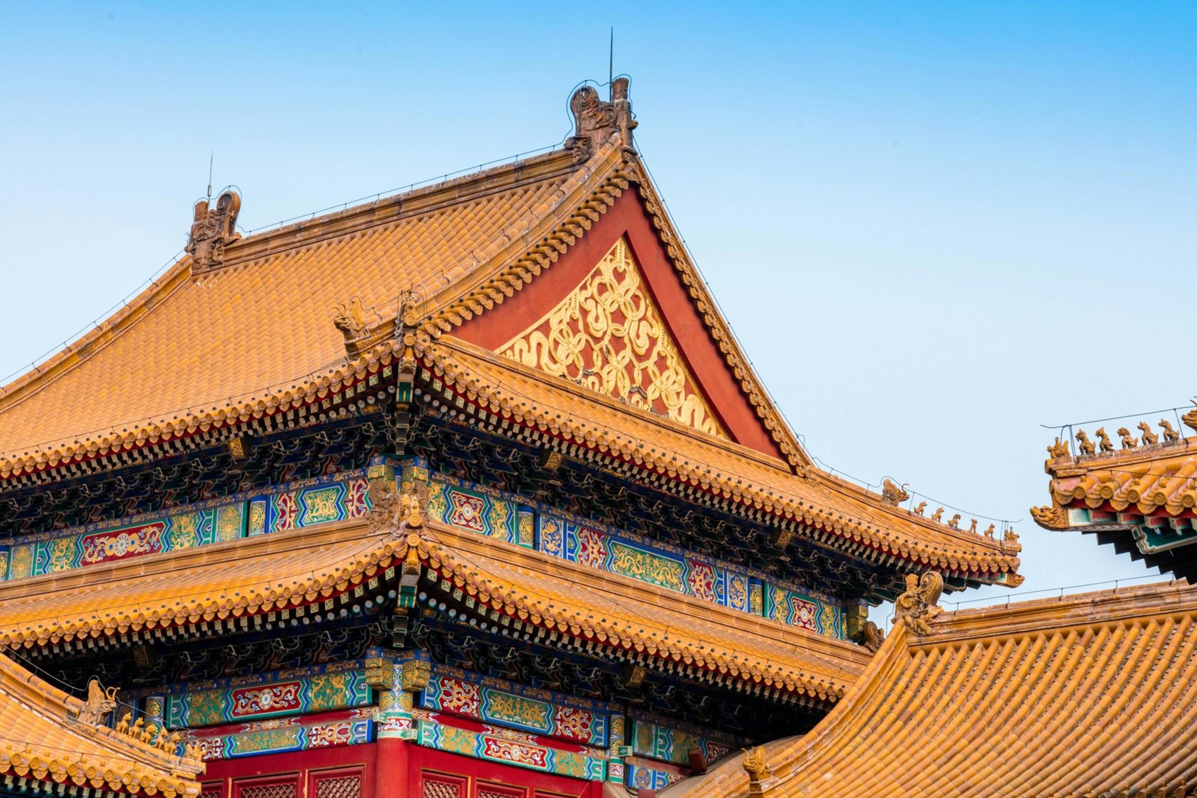 Close-up of the ornate roof architecture of Beijing's Forbidden City, showcasing detailed carvings and vibrant colors.