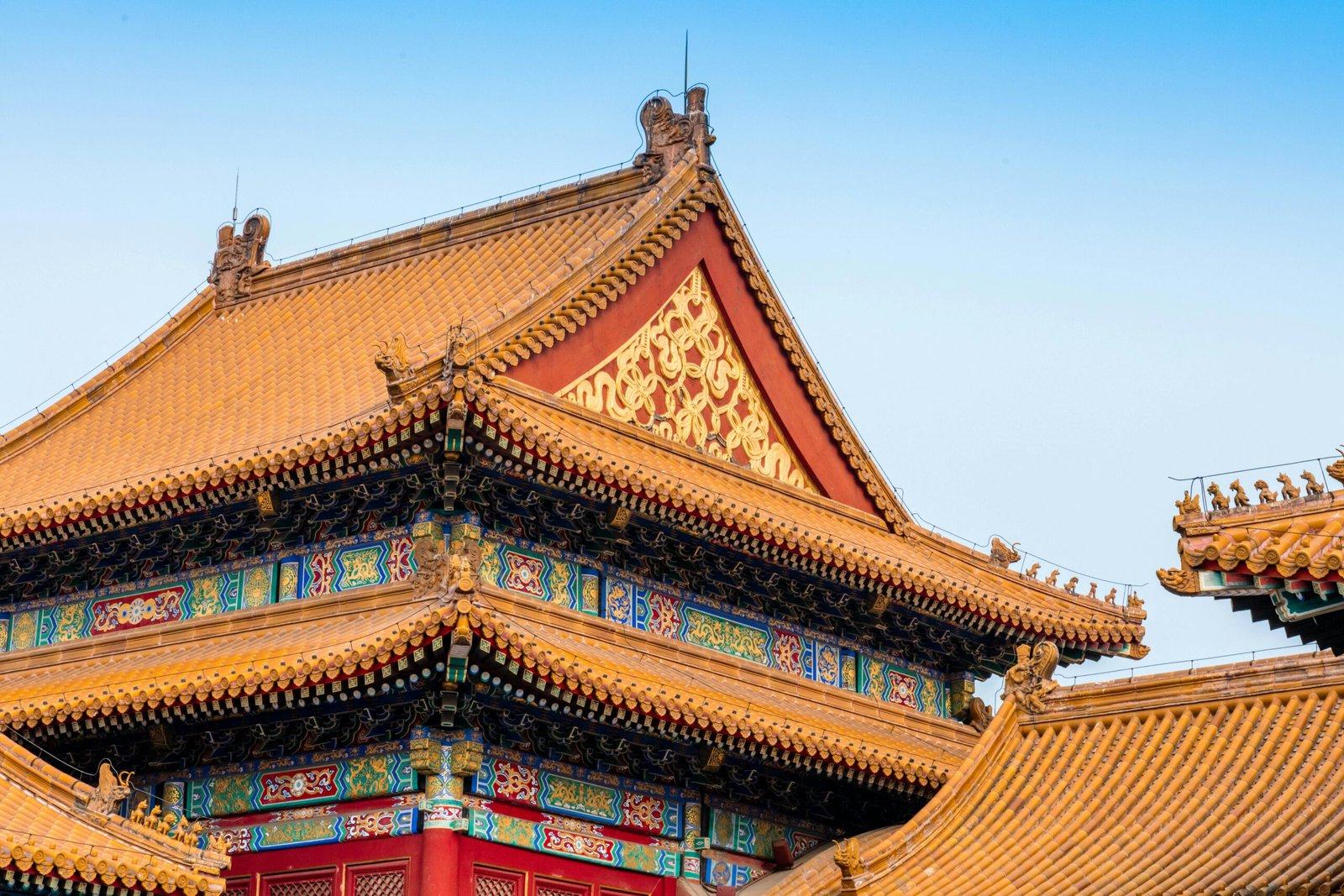 Close-up of the ornate roof architecture of Beijing's Forbidden City, showcasing detailed carvings and vibrant colors.