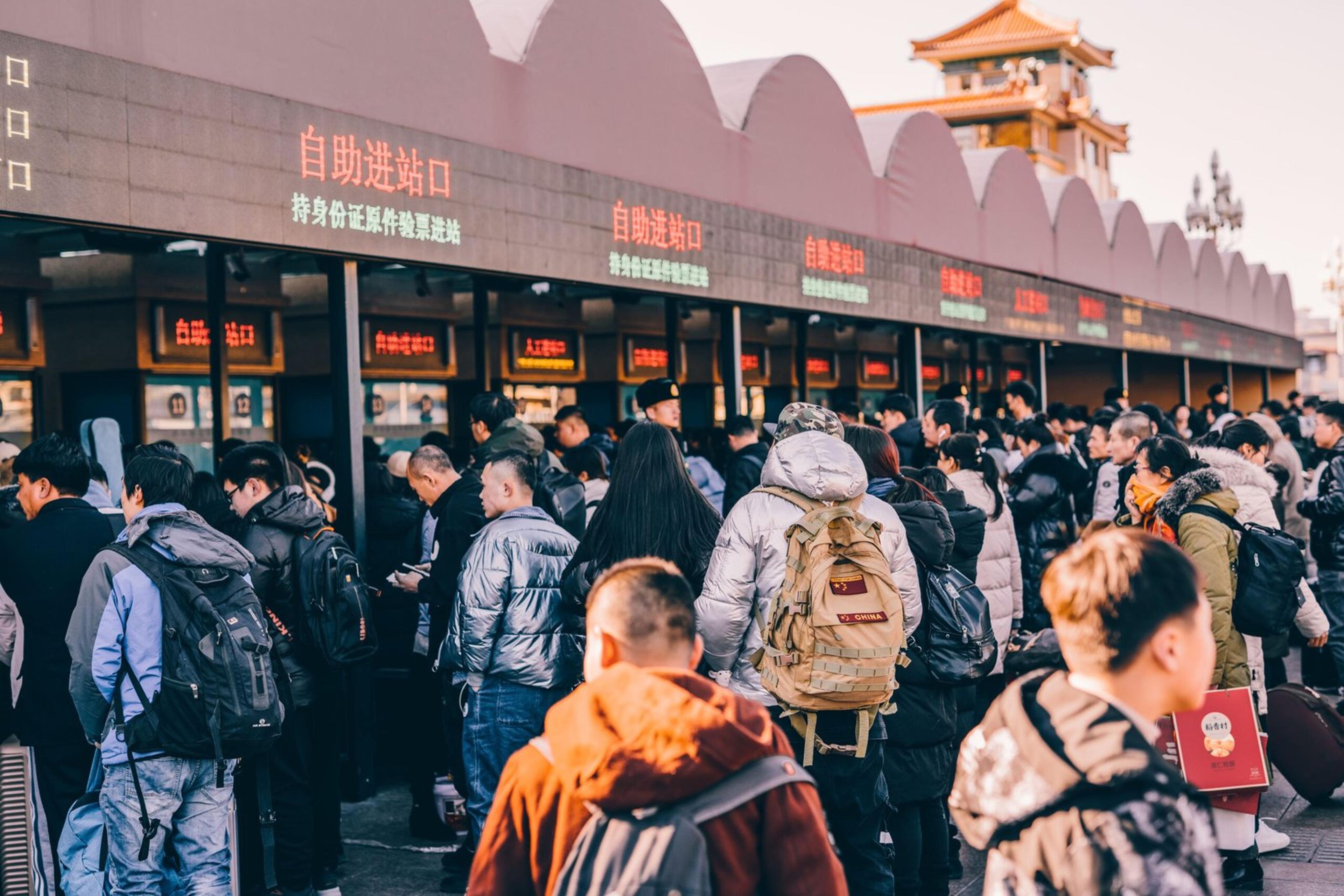 A crowd of people waiting in line at a ticket station in Beijing, China, showcasing modern urban life.