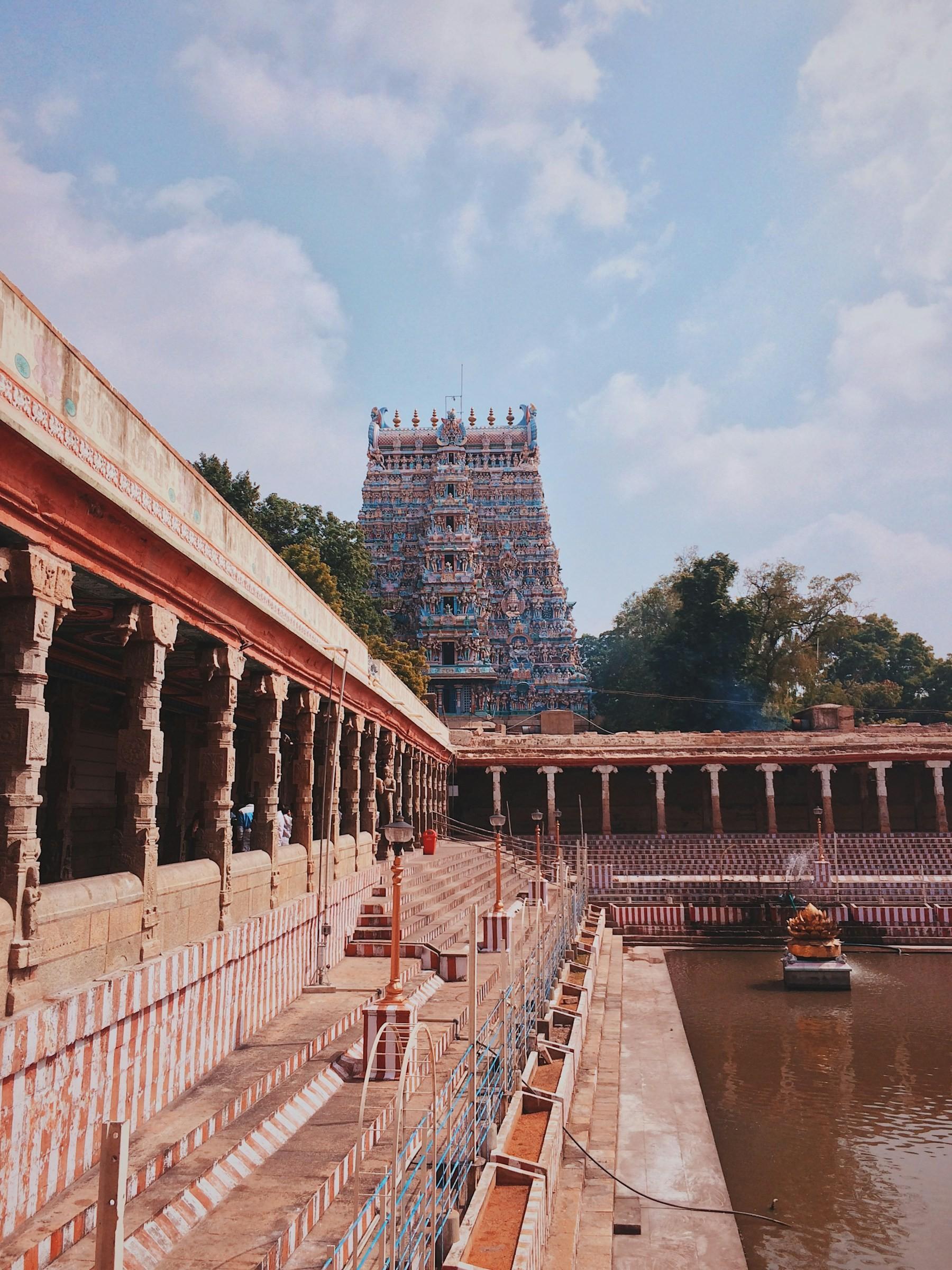 The temple tank and pillared corridors of a South Indian temple, with its gopuram behind