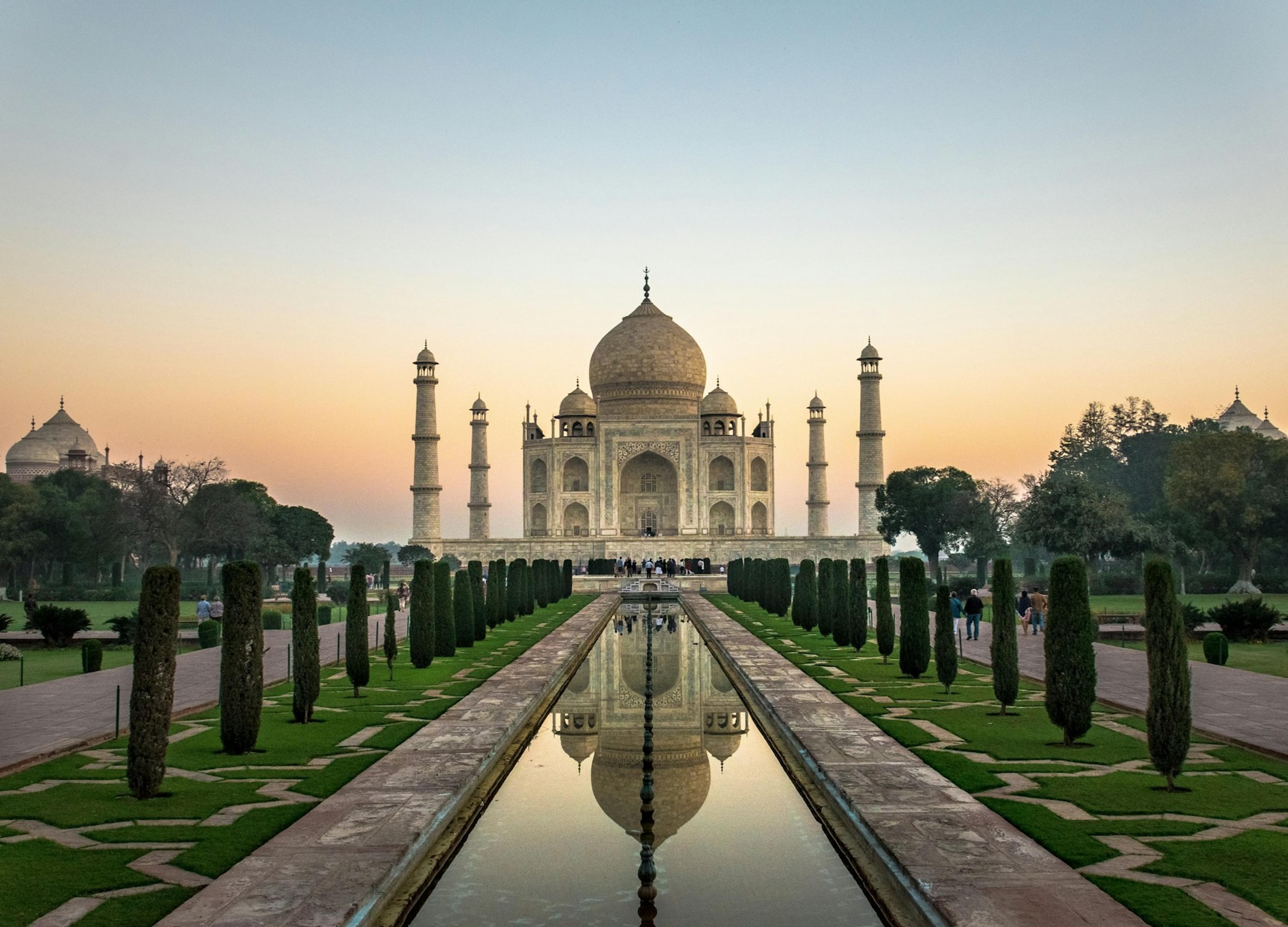 The Taj Mahal at sunrise, reflected in the long pool of its Mughal garden, Agra