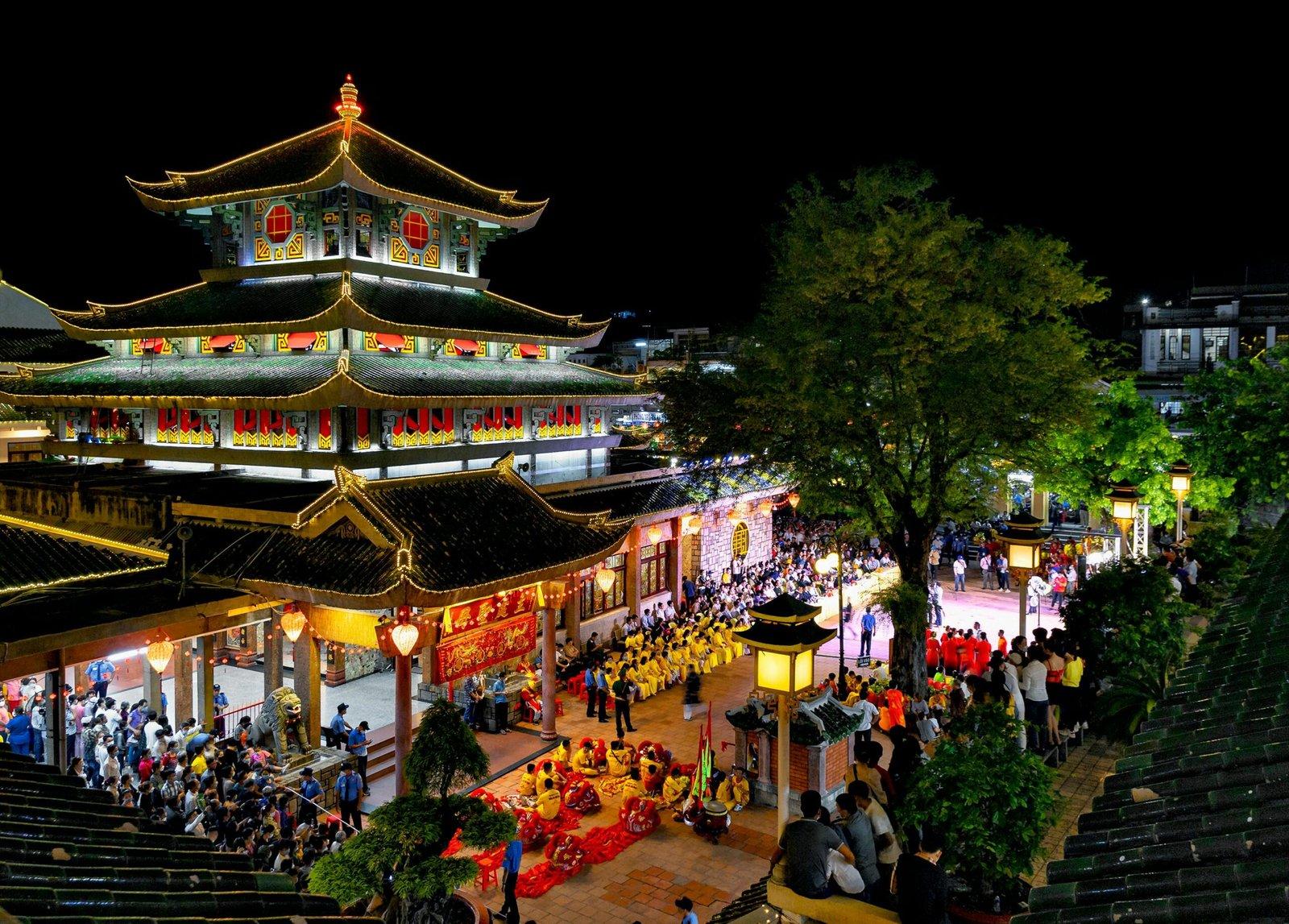 Brightly lit pagoda during a traditional festival in An Giang, Vietnam, showcasing cultural and architectural beauty.