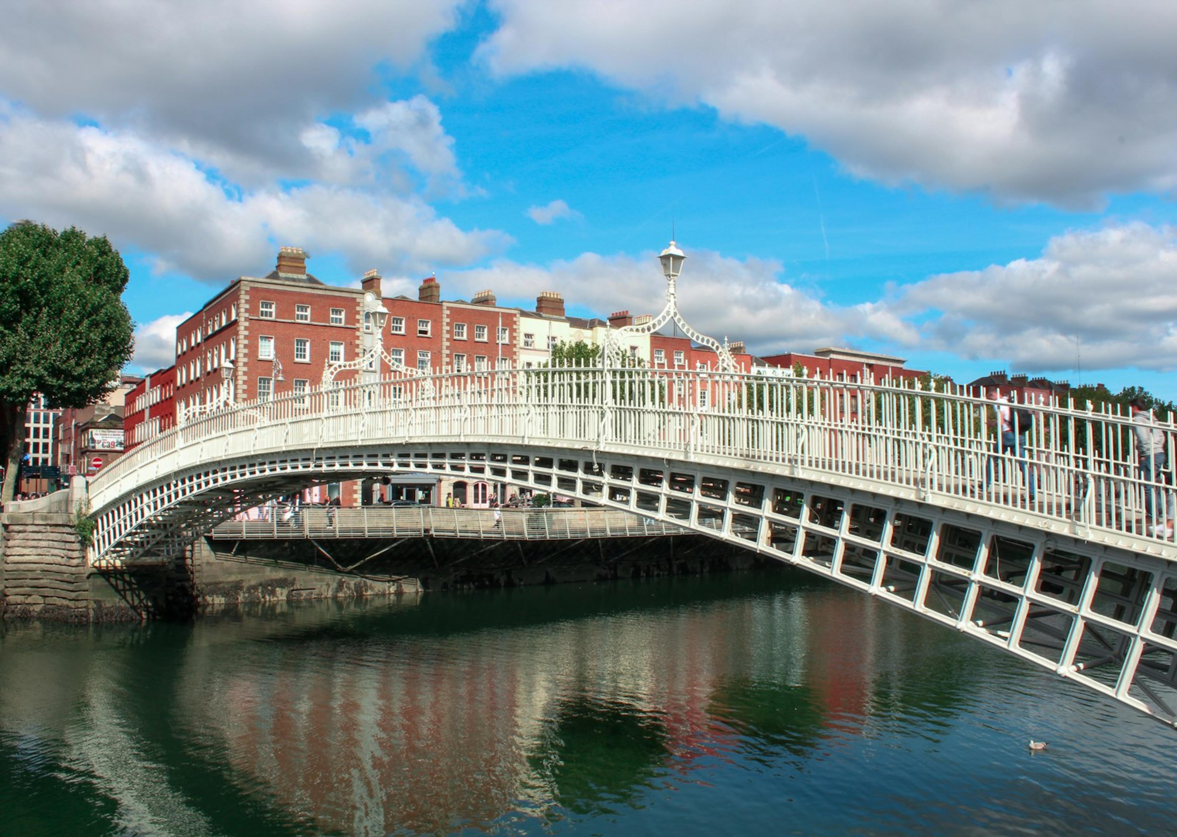 The white iron Ha'penny Bridge over the River Liffey in Dublin, with red-brick buildings behind it