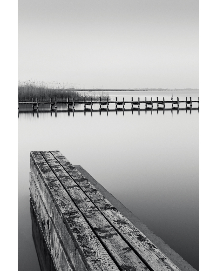 Wooden pier reflected in calm black and white water