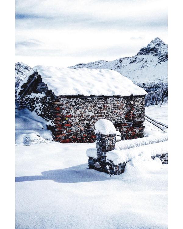 Stone cabin surrounded by snow and mountains