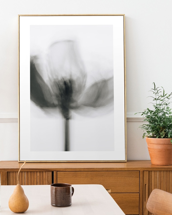 Blurred Tulip Study poster in a slim gold frame leaning on a wooden sideboard in a bright dining room