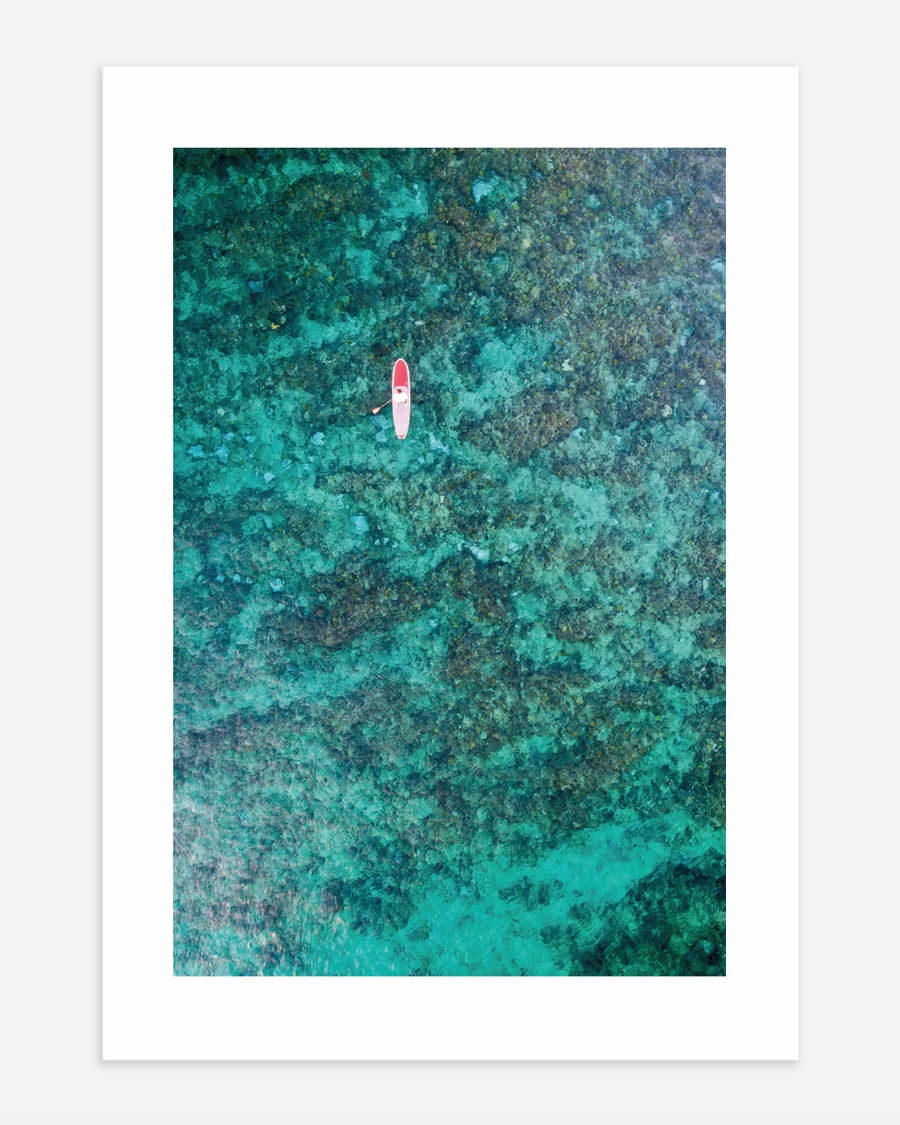 A poster of a Aerial paddleboarder floating above turquoise coral reef