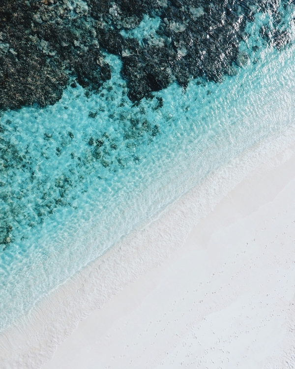 A tranquil aerial view of turquoise waves meeting soft white sand