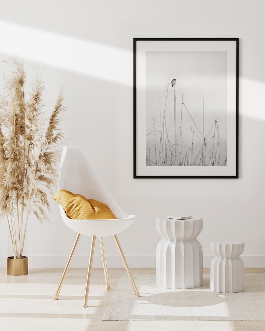 Perched Above the Reeds poster in a slim black frame above a white chair in a bright boho living room