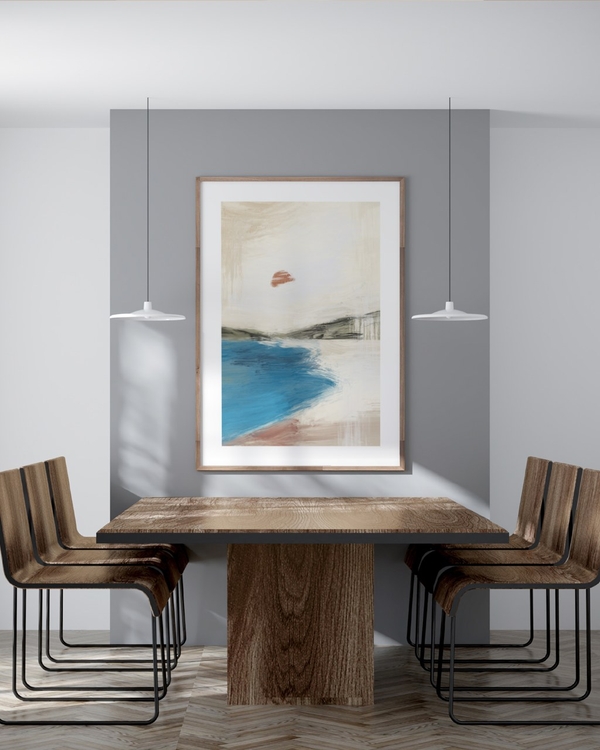 Red Sun Bay poster in a light wood frame above a wooden dining table between two pendant lamps