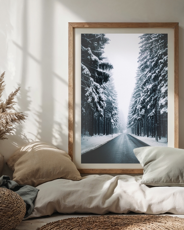 A poster of a Empty winter road lined with snow-covered pine trees.