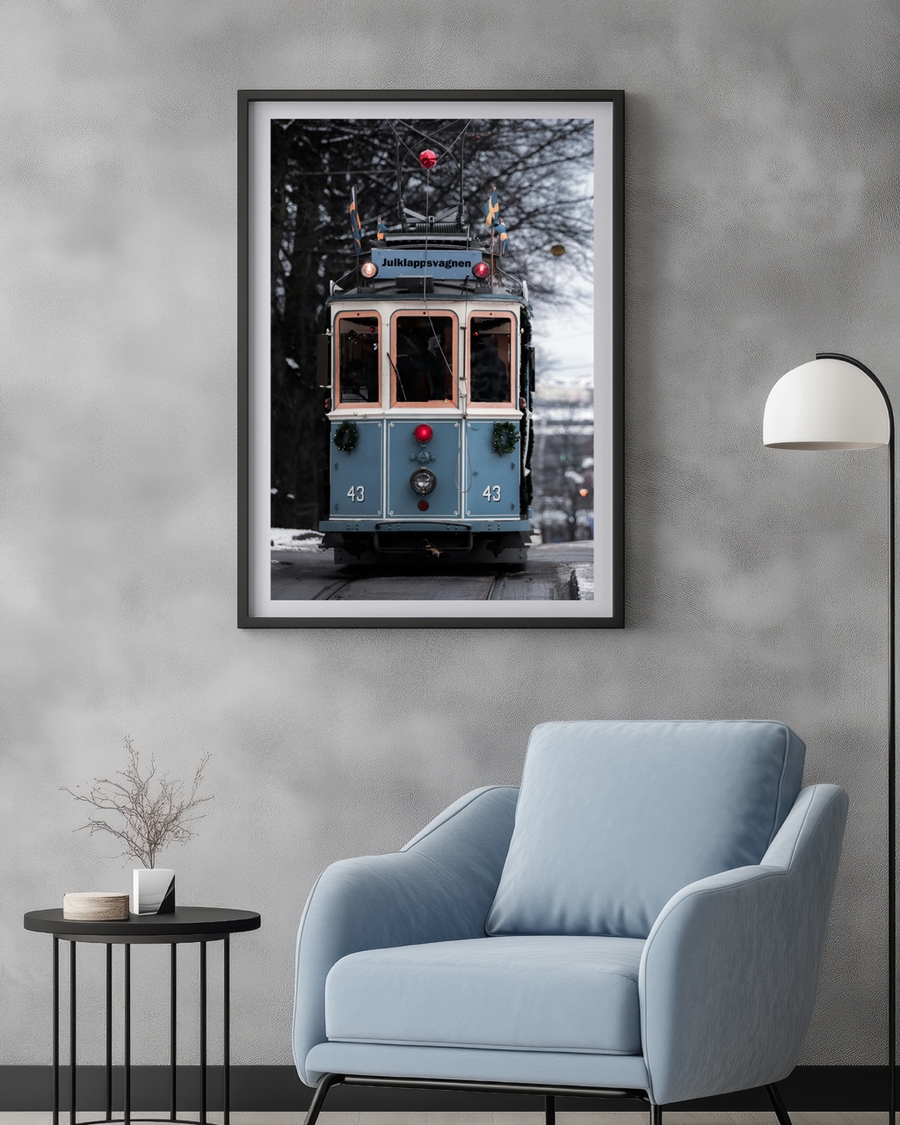 A poster of a blue vintage tram decorated for Christmas on snowy street