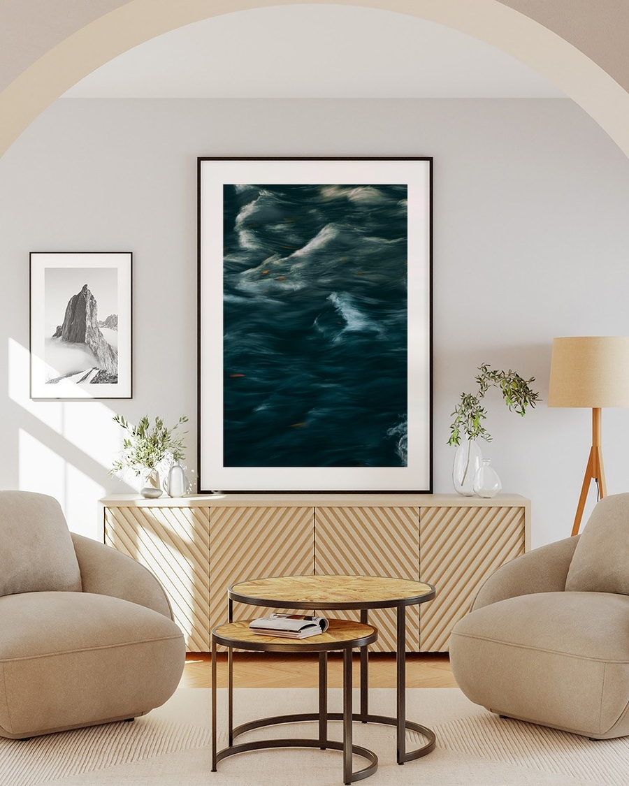 Teal Current poster in a black frame above a wooden sideboard in a bright living room