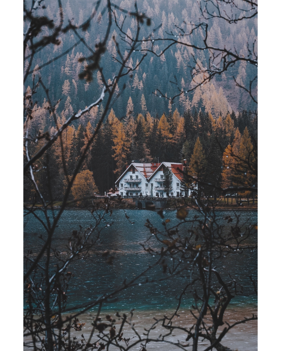 White house by lake surrounded by autumn forest