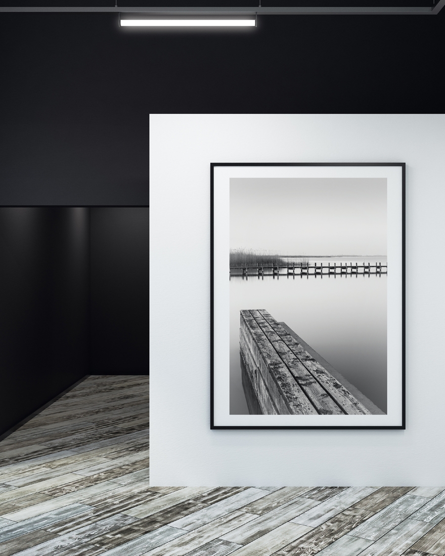 A poster of a Wooden pier reflected in calm black and white water