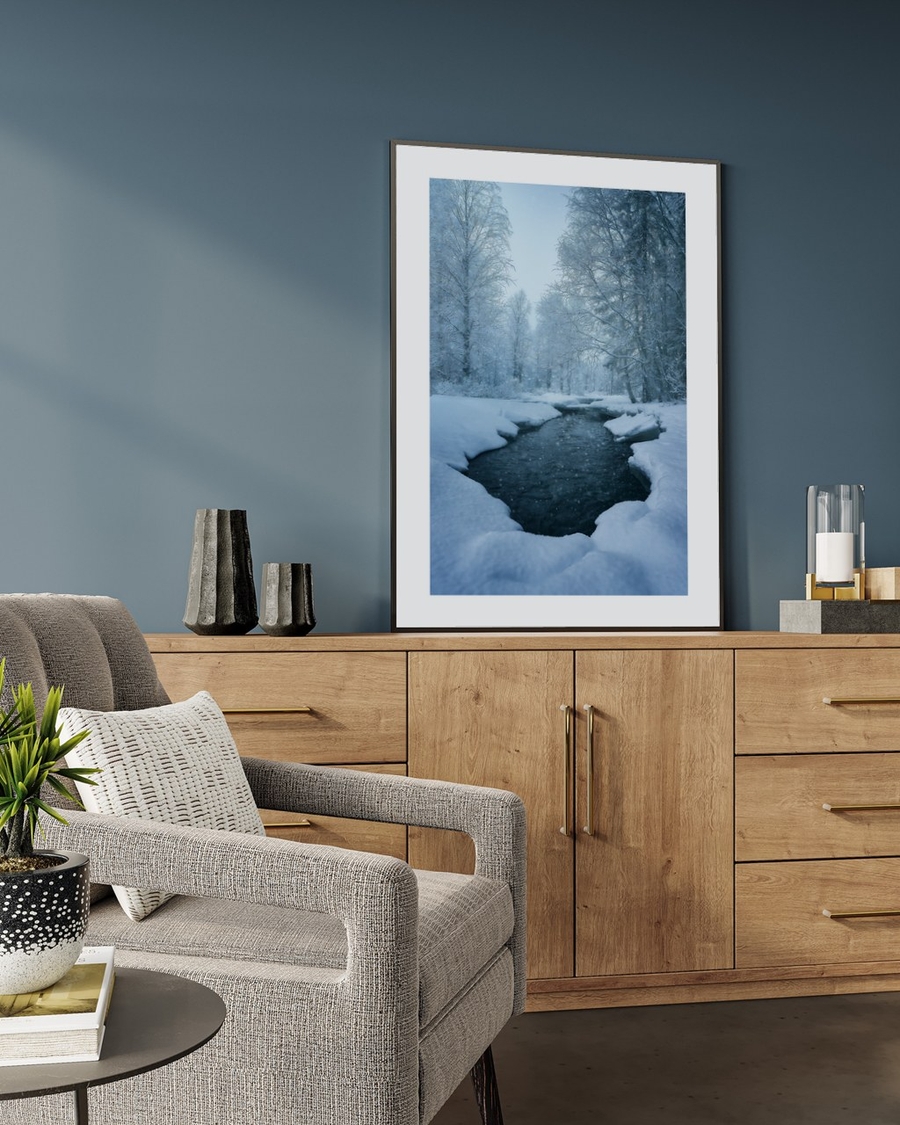 Snowlined Brook poster in a slim black frame leaning on an oak sideboard against a blue-grey wall