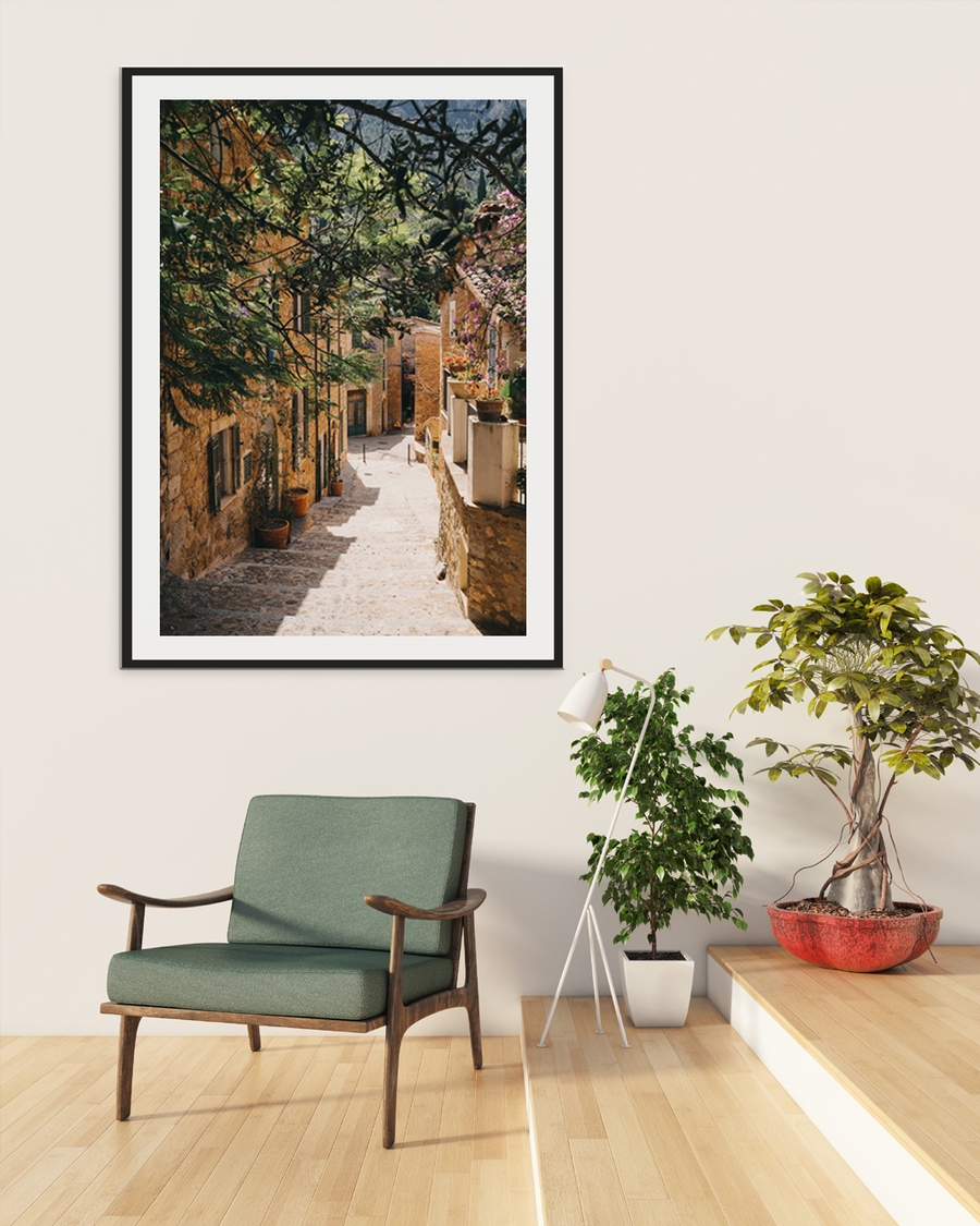A poster of a sunlit Mediterranean alley with stone houses and flowers