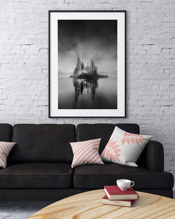 Island of Light poster in a black frame on a white brick wall above a dark sofa