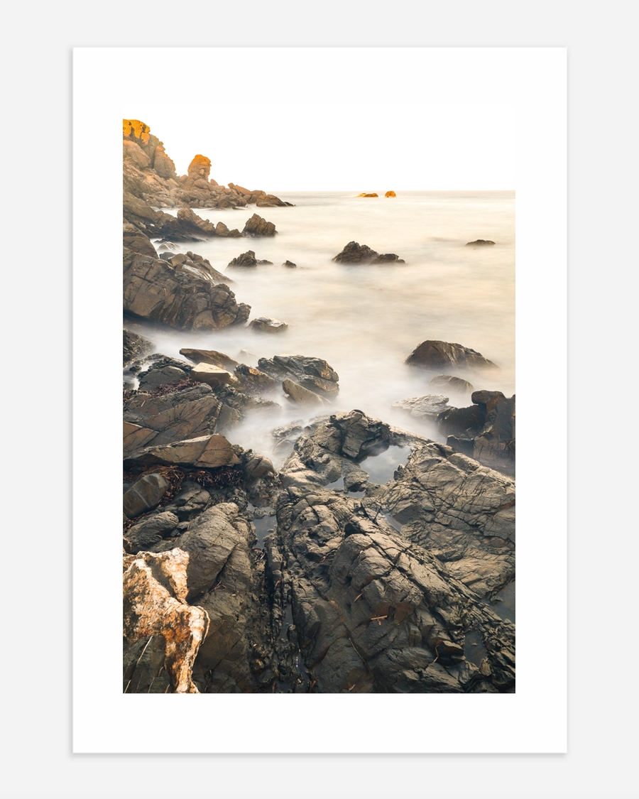 A poster of a Rocky coastline with misty water and soft light