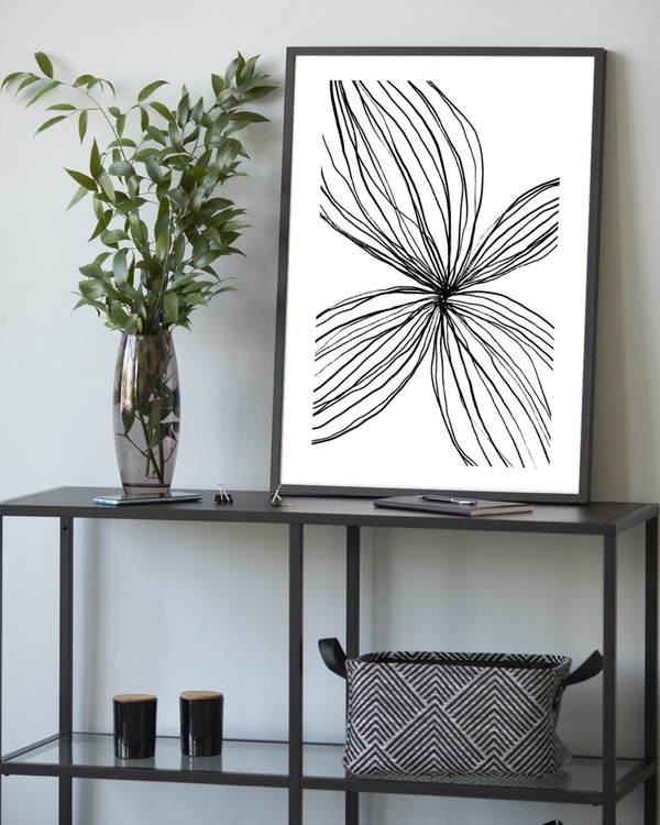 Petal Lines poster in a slim black frame leaning on a metal console table with greenery