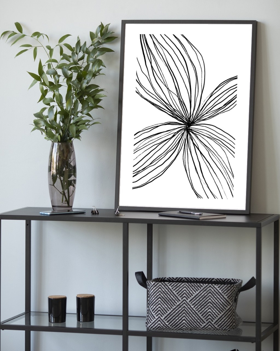 Petal Lines poster in a slim black frame leaning on a metal console table with greenery