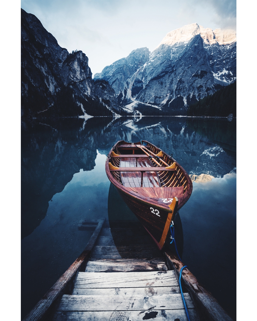Wooden boat moored on calm alpine lake with mountains