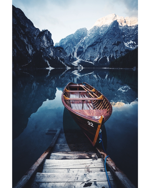Wooden boat moored on calm alpine lake with mountains