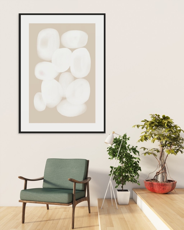 Chalk Pebbles poster in a black frame with white mat above a green armchair in a bright minimal room