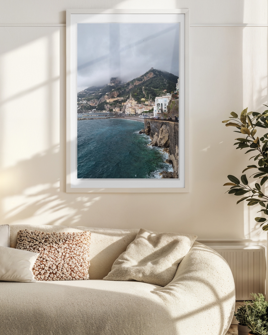 A poster of a Colorful cliffside town overlooking turquoise sea under cloudy sky.